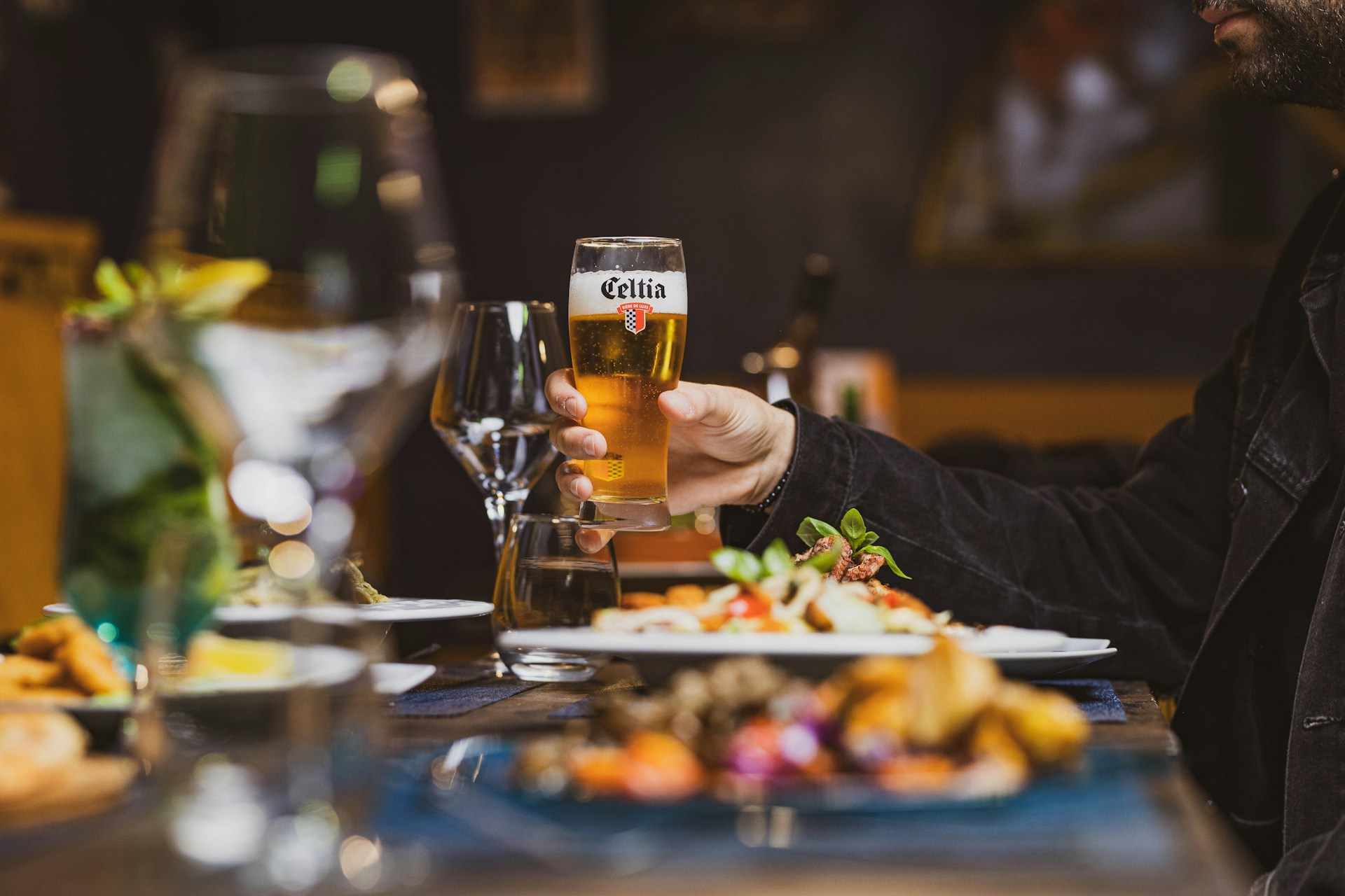 A man sitting at a table with a plate of food and a glass of beer