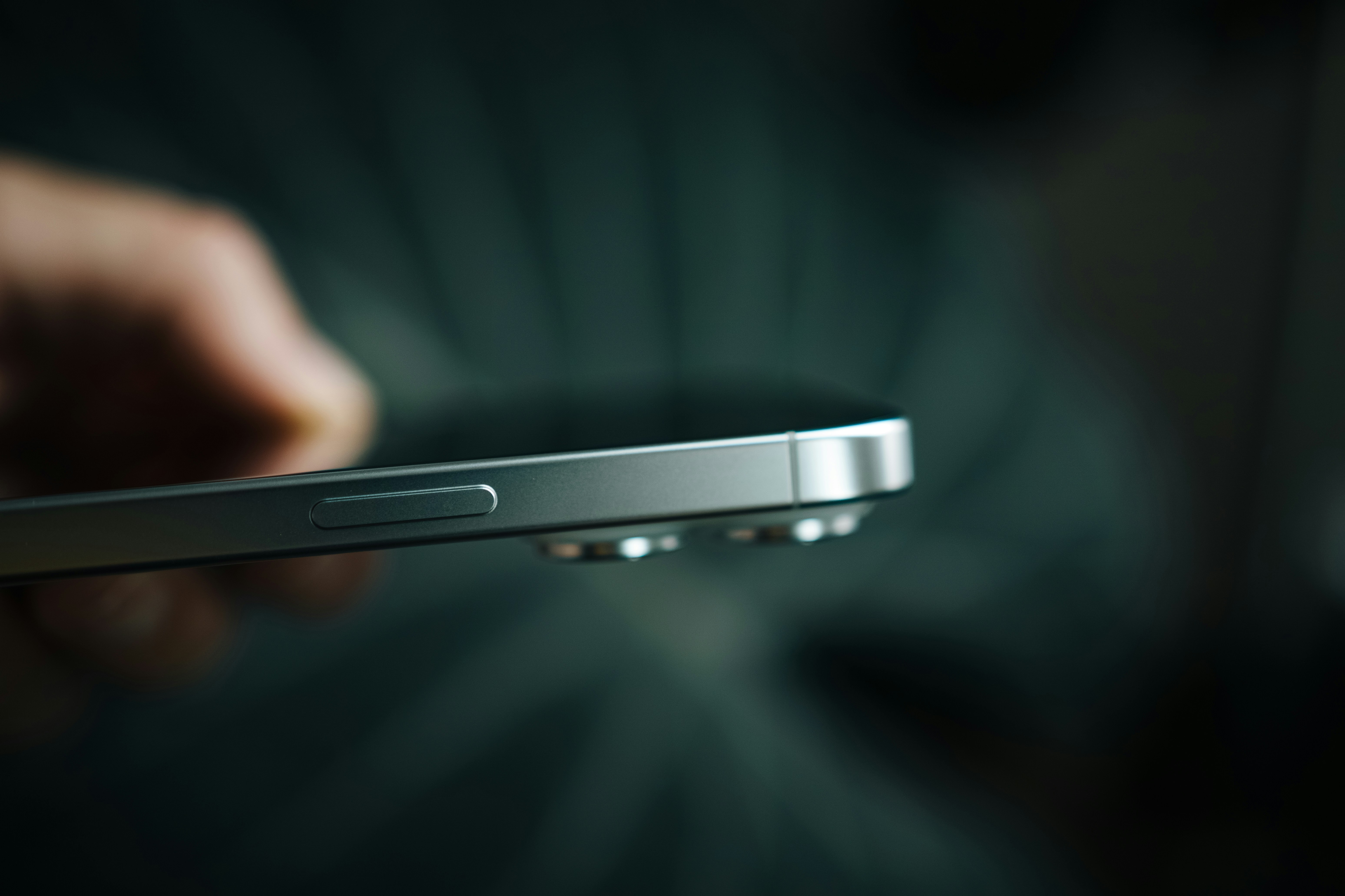 A close up of a person holding a cell phone, A detailed close-up of a smartphone from side, focusing on the smooth side profile and power button. The shallow depth of field emphasizes the precision and quality of the device’s design. The image highlights the seamless, minimalistic aesthetic that is a hallmark of modern tech devices, creating a sleek and sophisticated look.