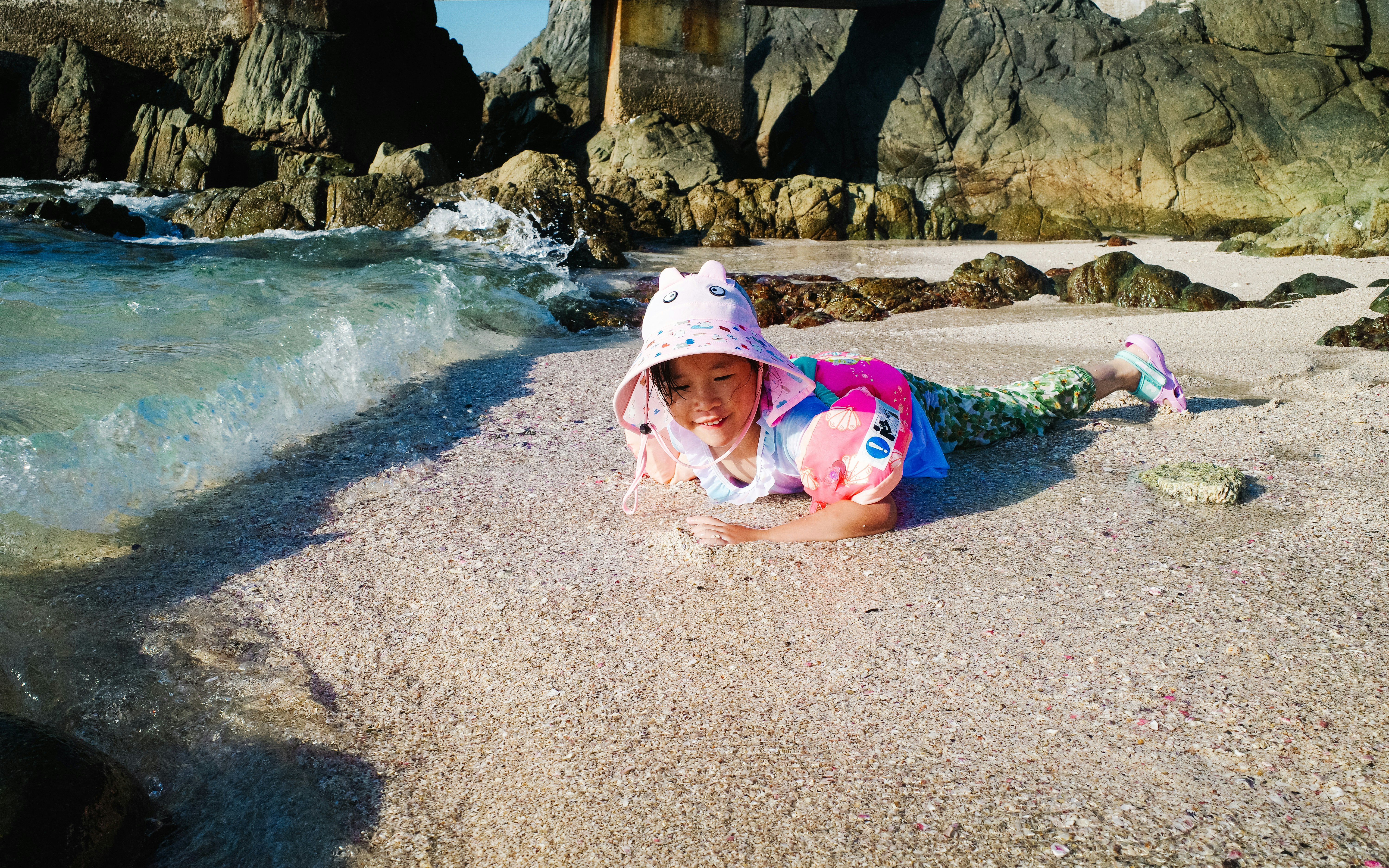 A little girl laying on top of a sandy beach