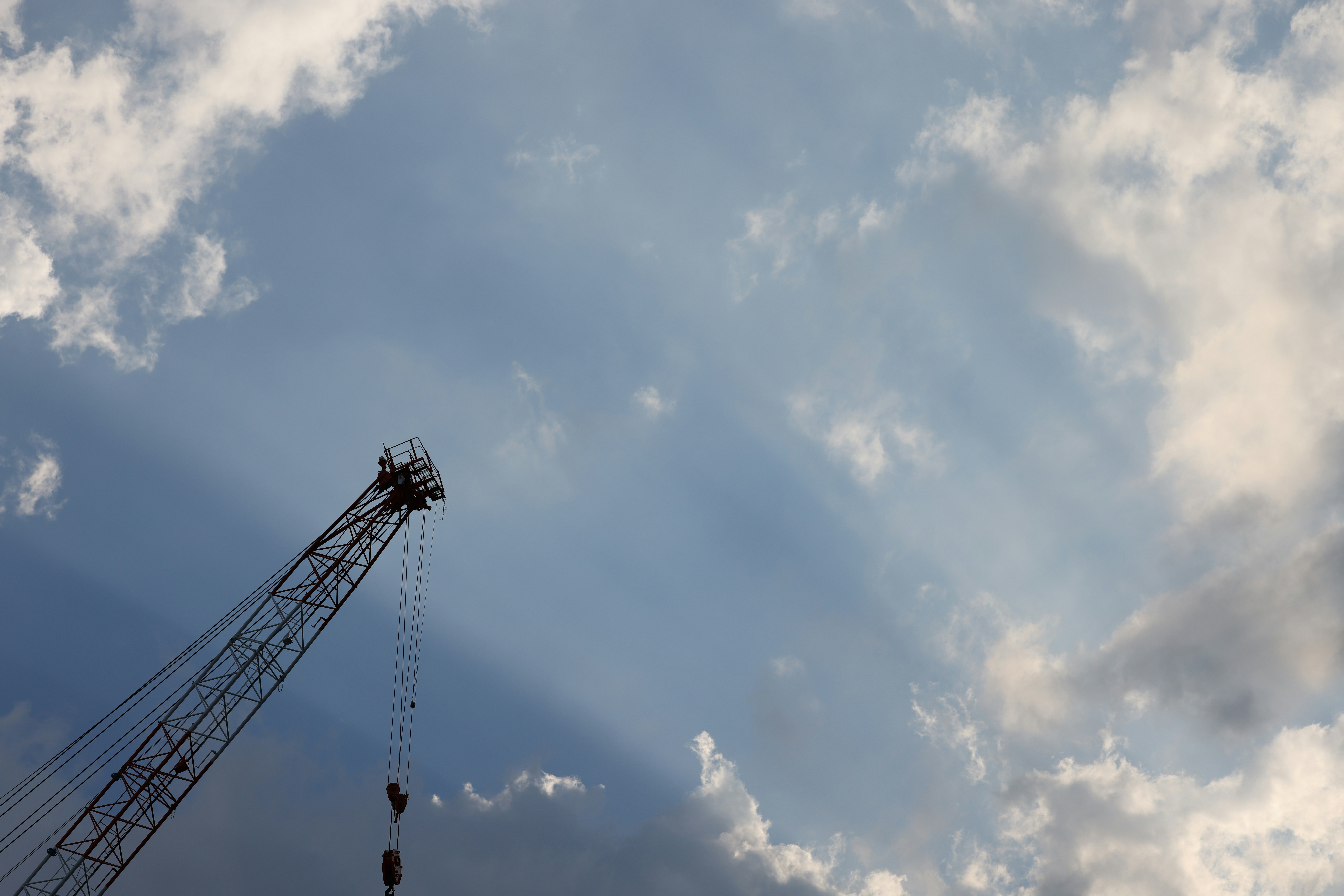 Construction site with large industrial crane against golden hour sky, dramatic shadows, epic industrial scale