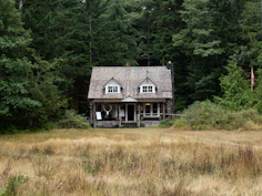 A house in the middle of a field with trees in the background