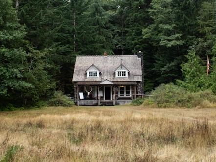 A house in the middle of a field with trees in the background