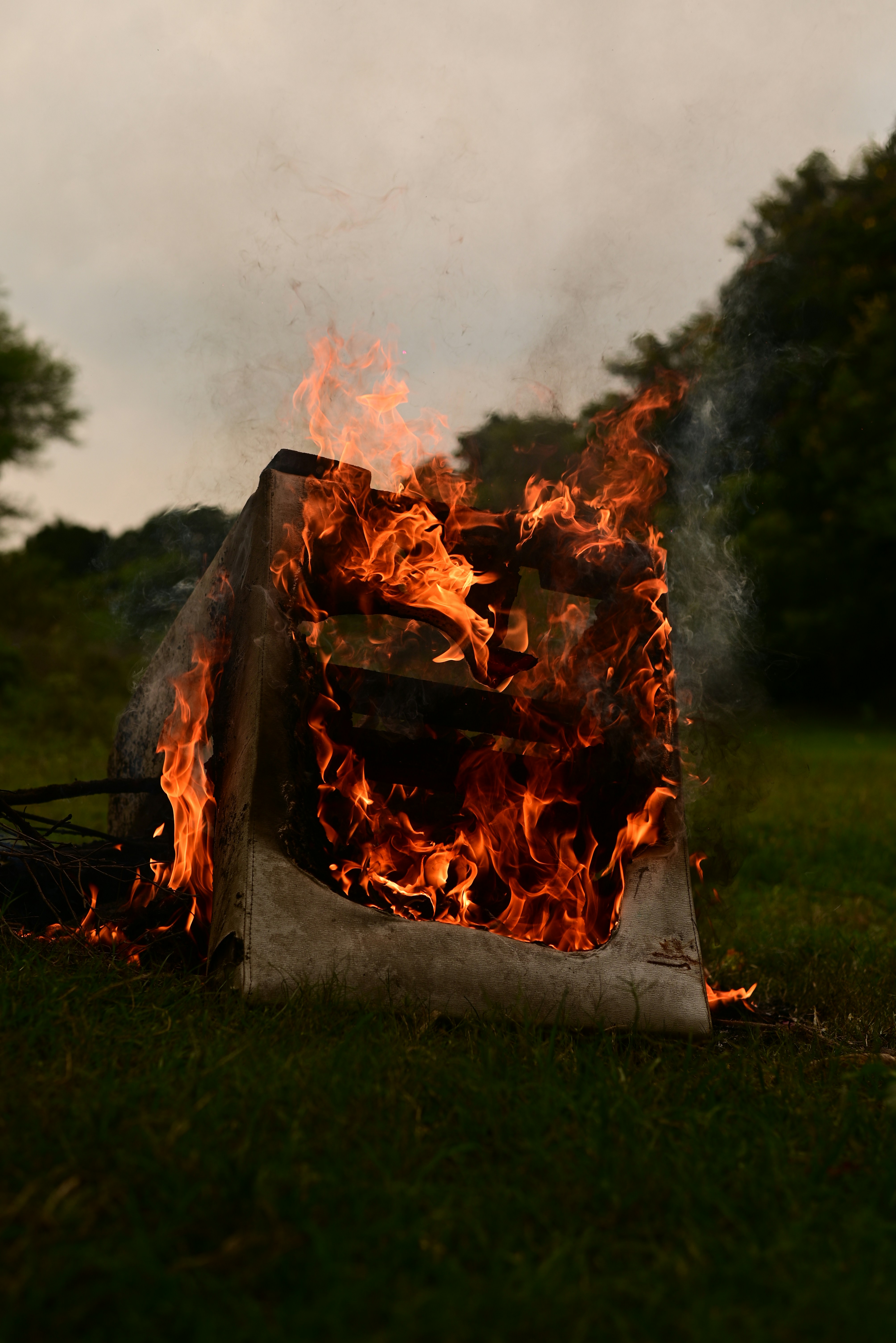 A fire burning in a field with trees in the background
