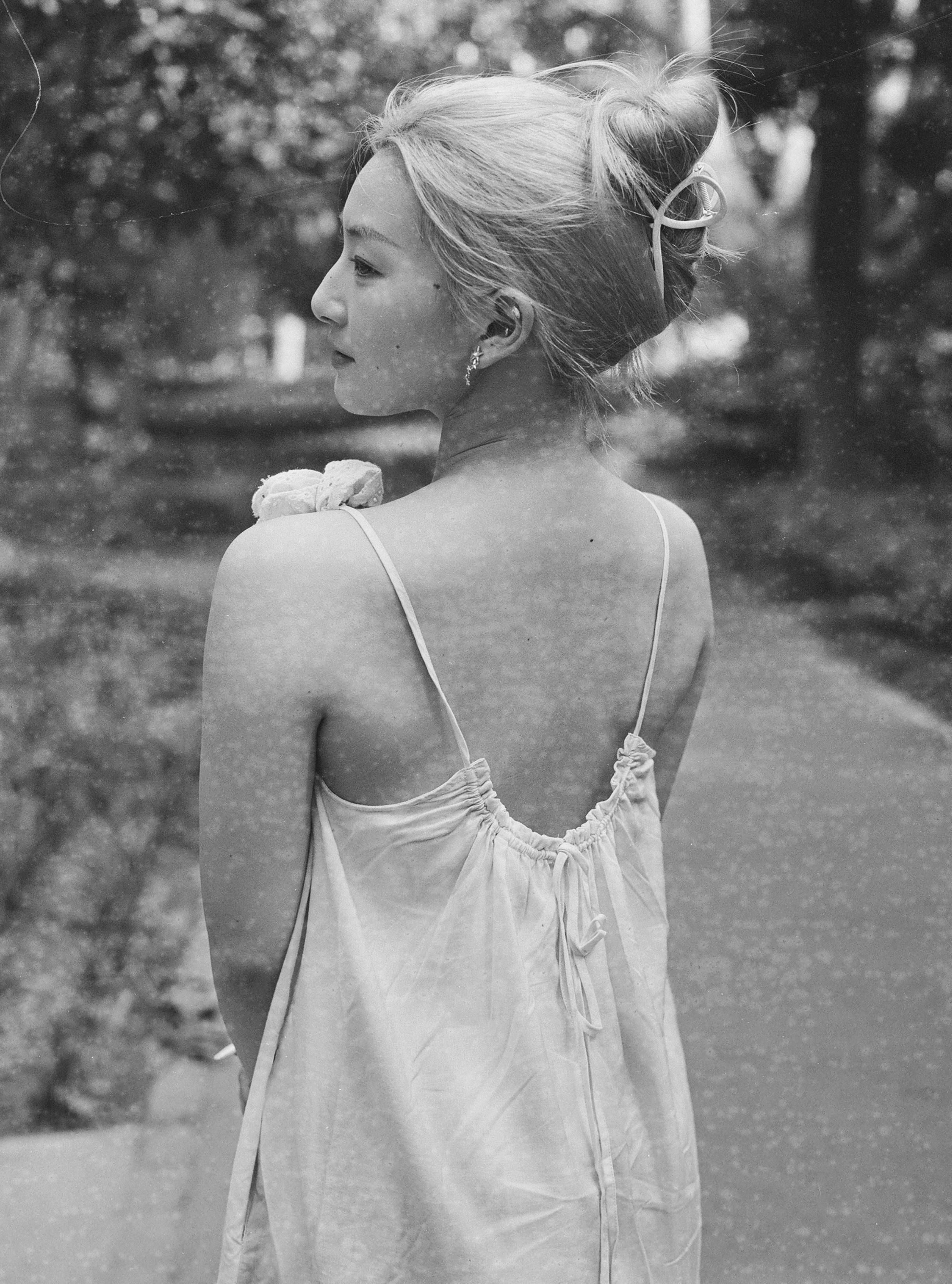 A woman standing on a sidewalk with her back to the camera