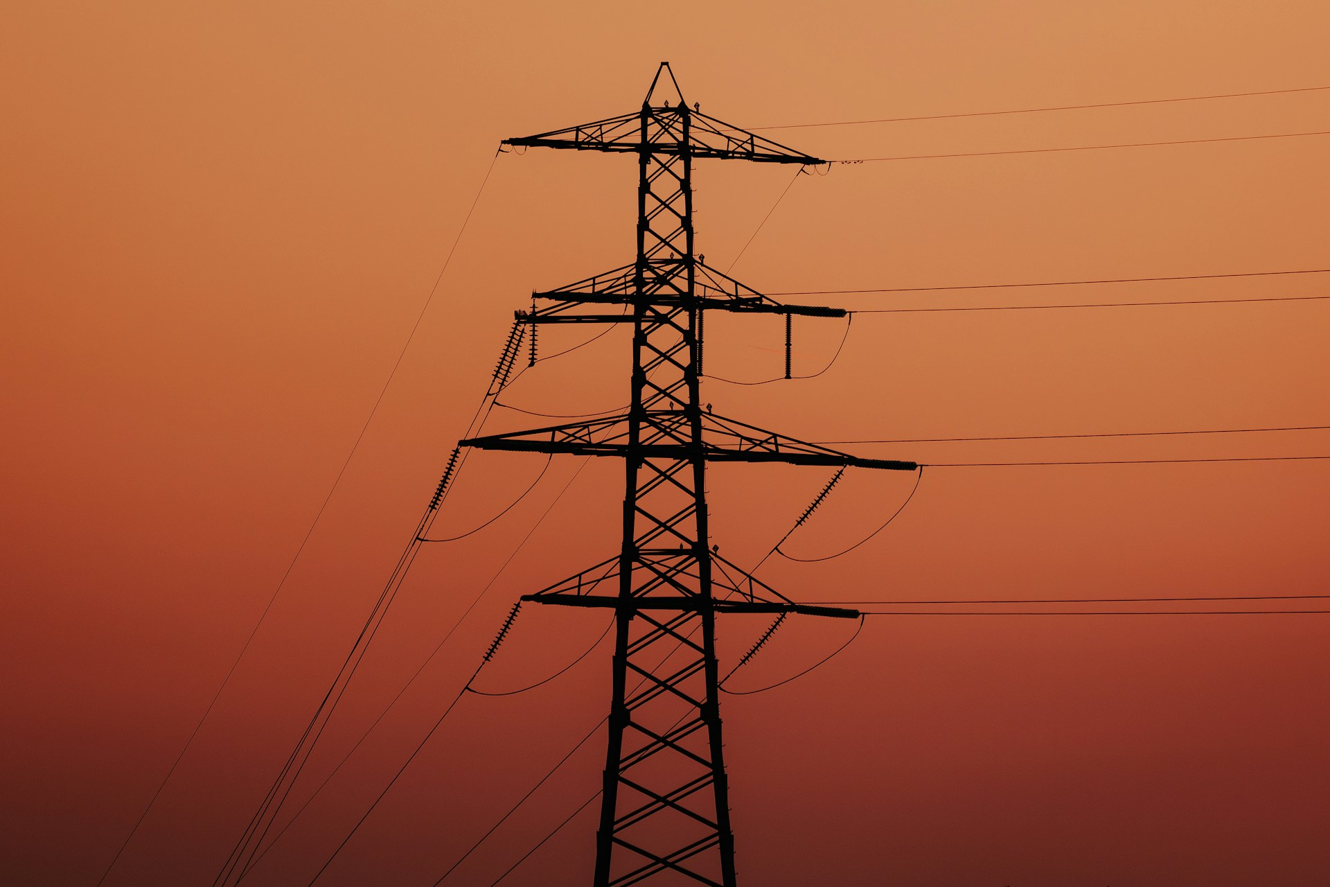 A high voltage power line with the sun setting in the background
