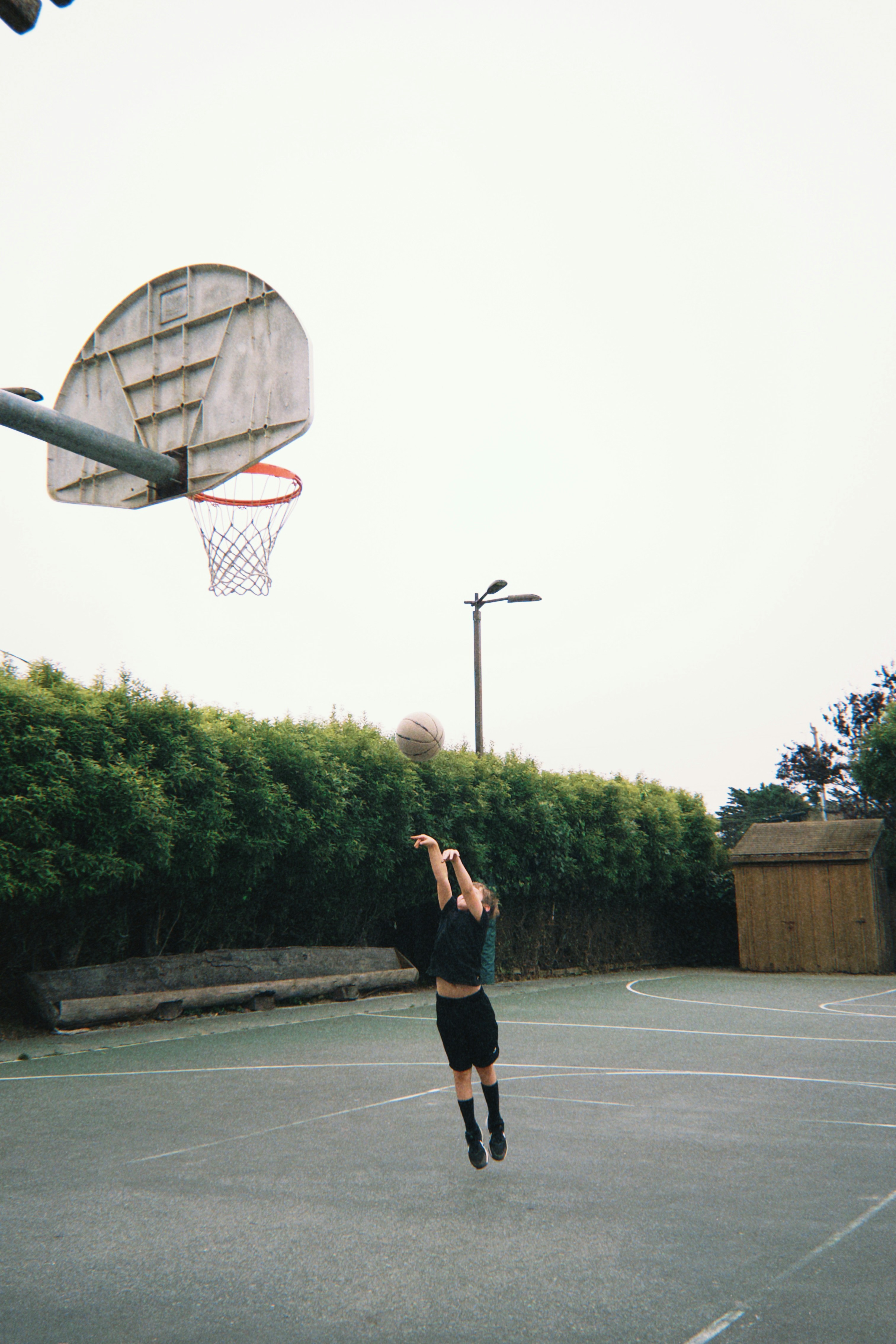 A person shooting a basketball on an outdoor court