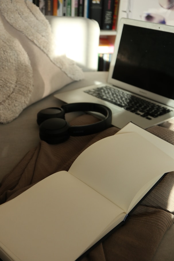 A laptop computer sitting on top of a bed next to a book