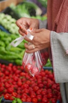 A woman holding a plastic bag in front of a display of vegetables