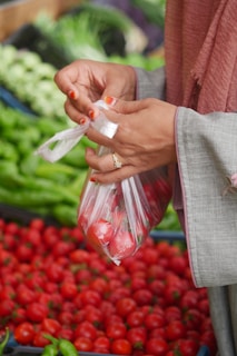 A woman holding a plastic bag in front of a display of vegetables