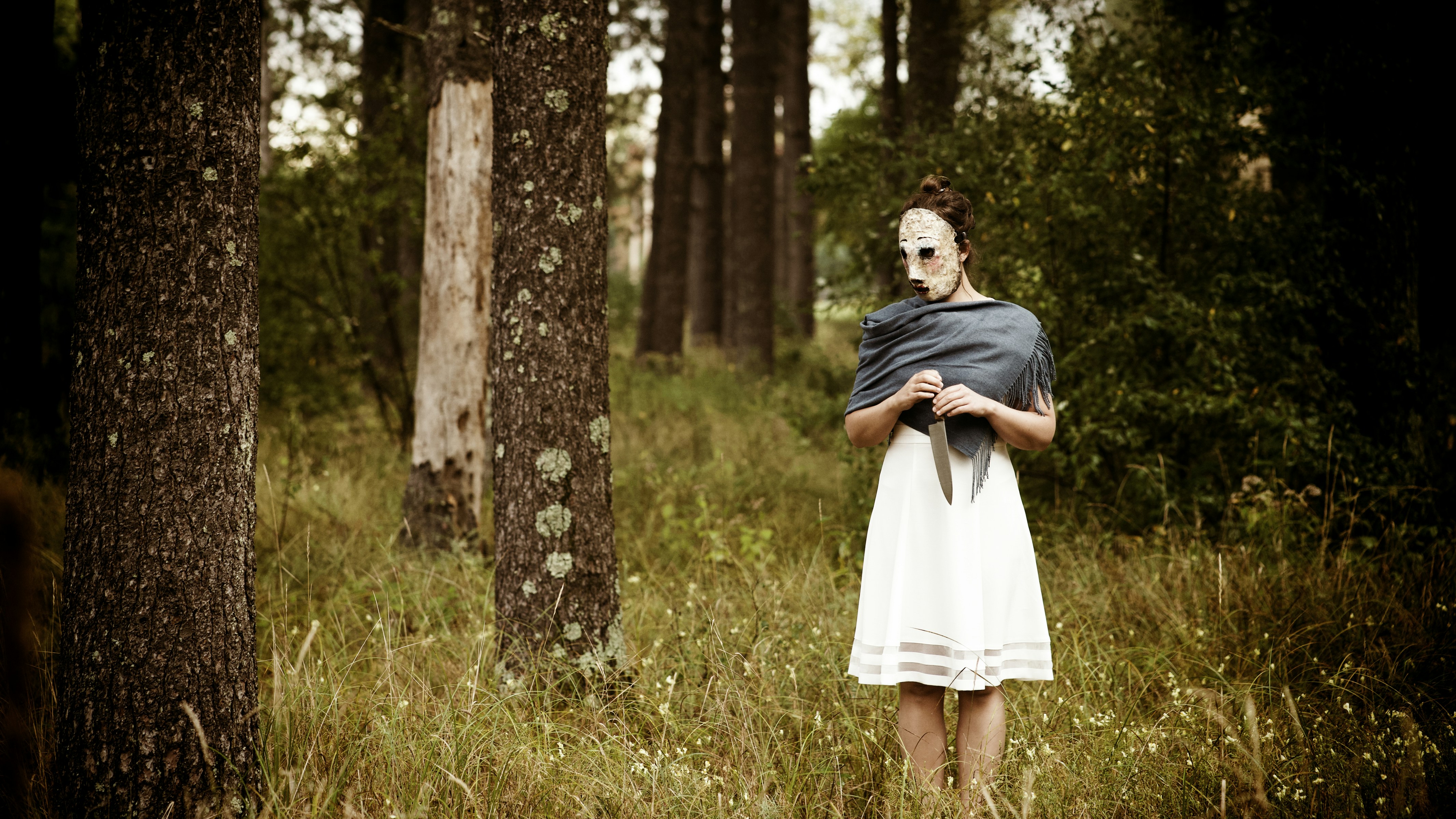 A woman in a white dress standing in a forest