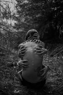 A person sitting on the ground in the woods