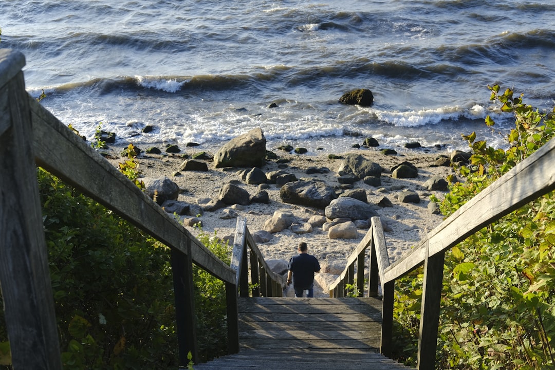 A person walking up a wooden staircase to the beach,
