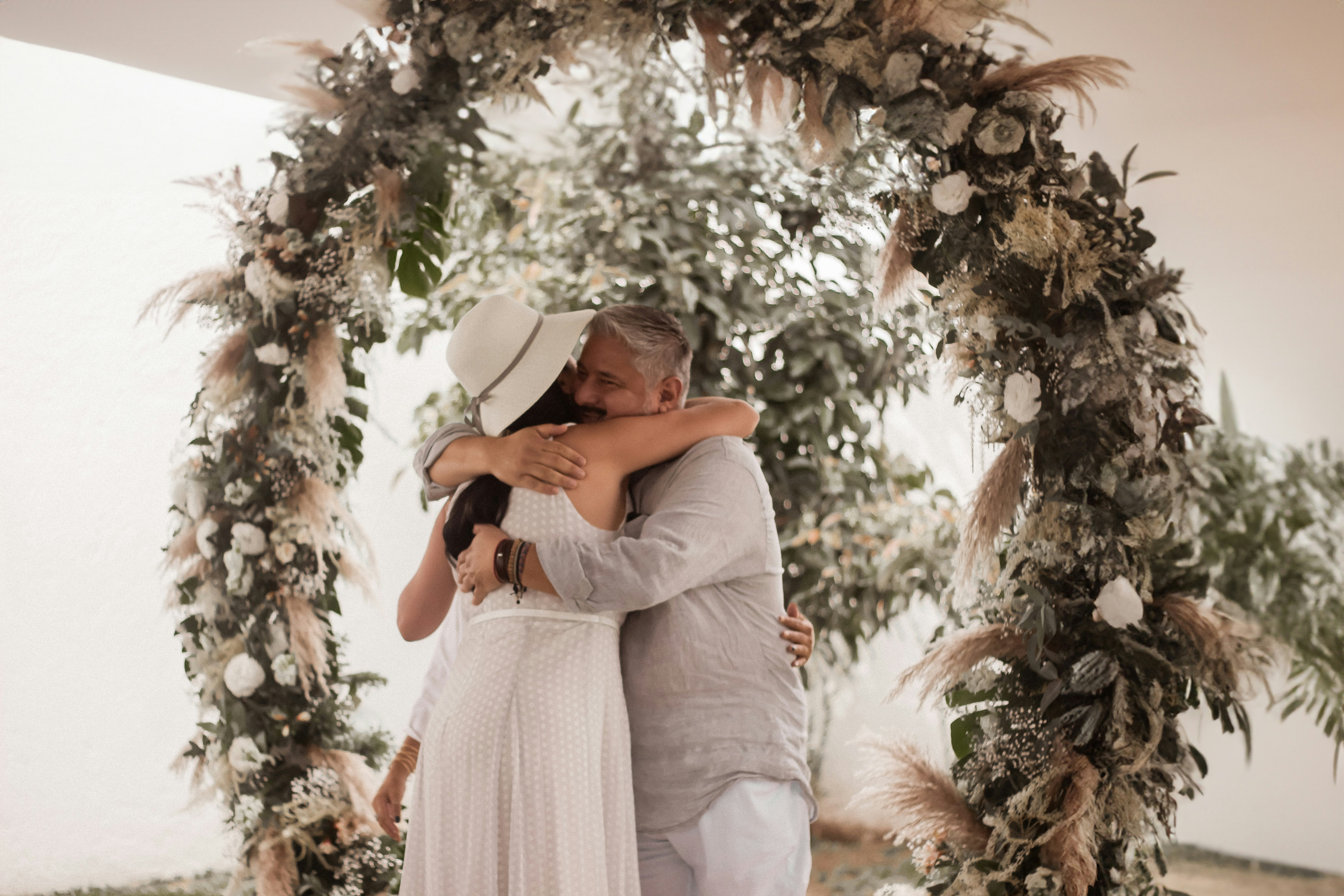 누에바파밀리아 - A man and a woman are hugging under a floral arch