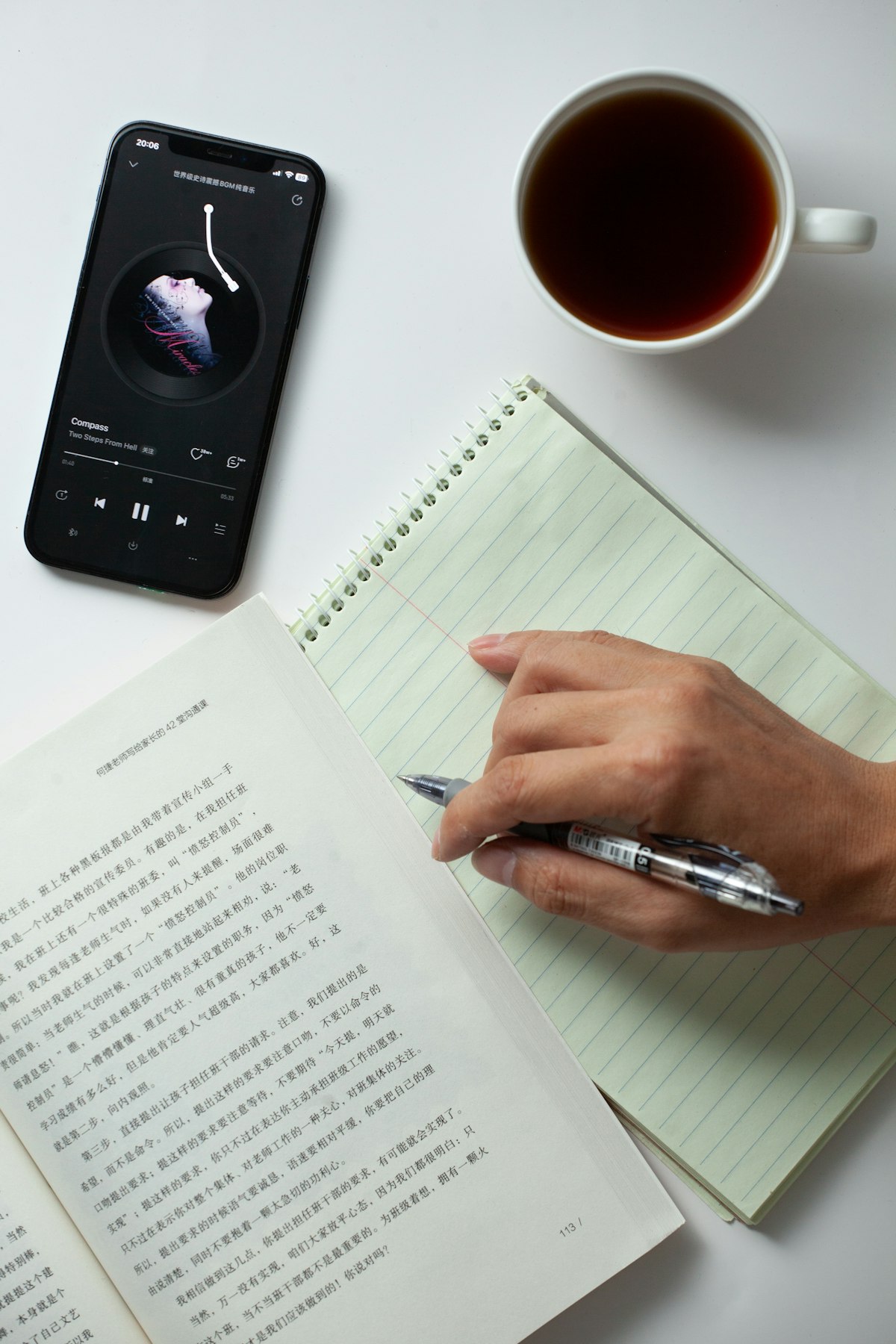 A notepad and pen next to a phone, mid-way through writing something down