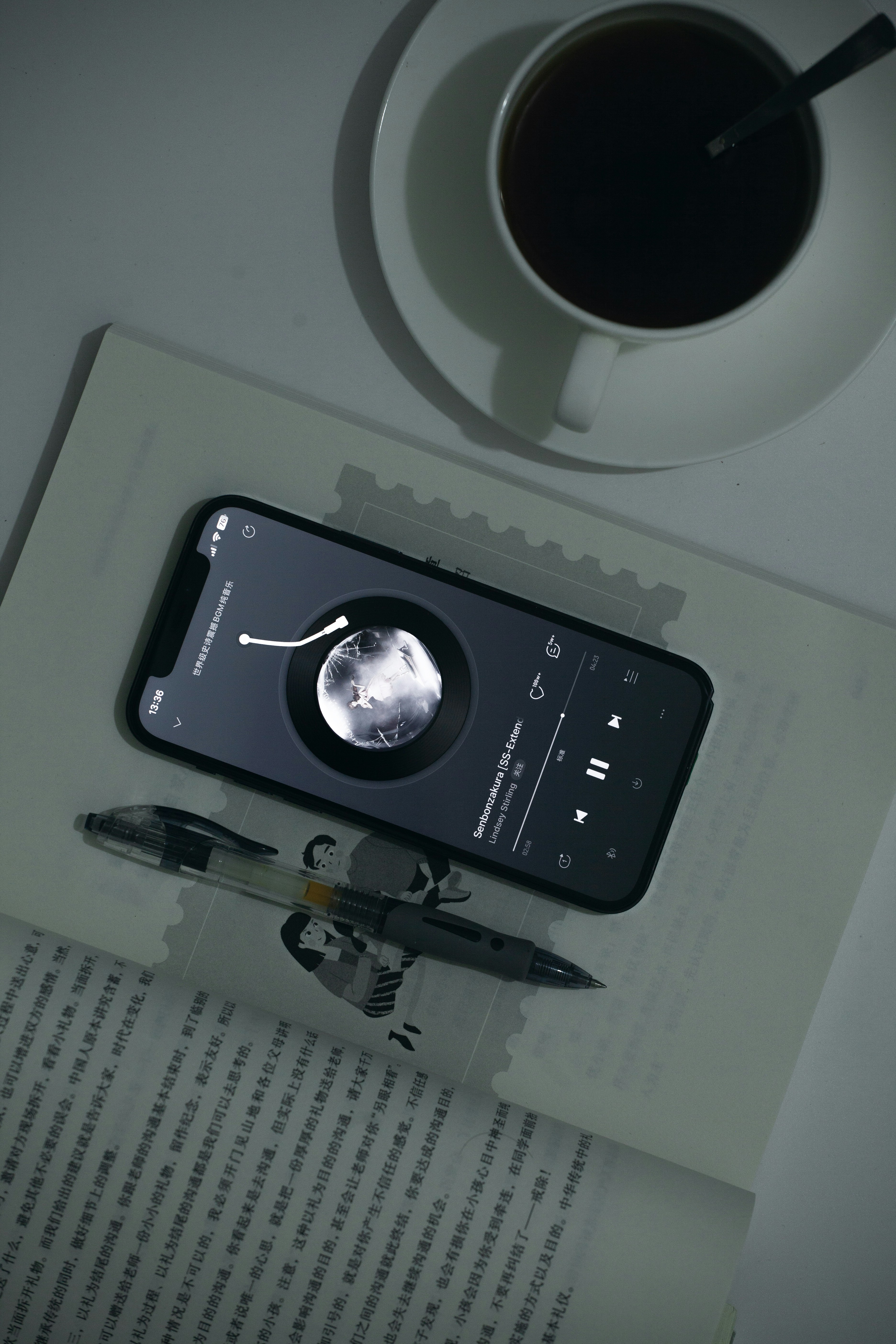 A cell phone sitting on top of a desk next to a cup of coffee