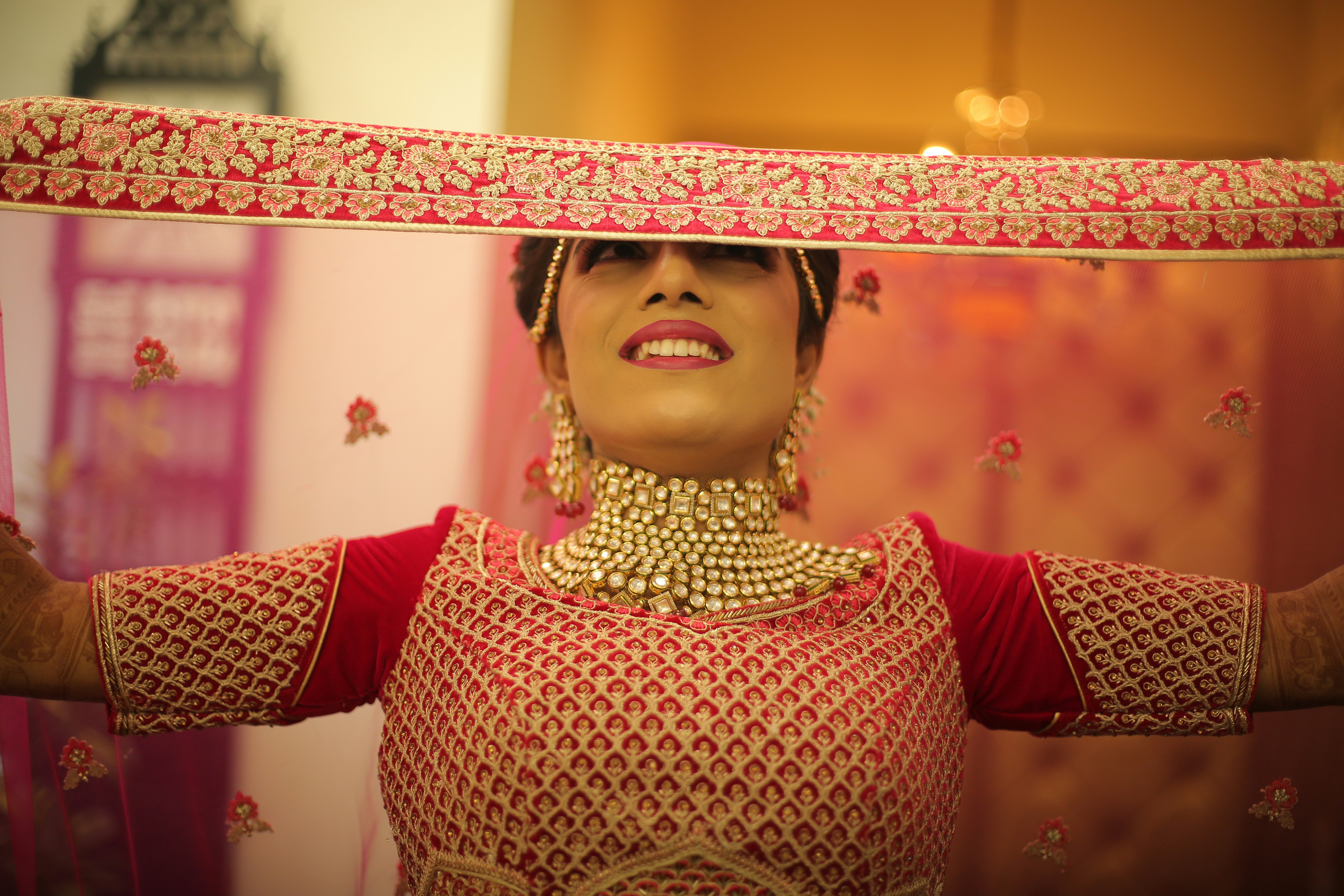 A woman in a red and gold outfit holding a piece of cloth over her head