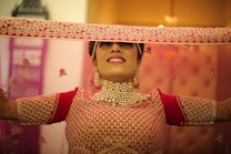 A woman in a red and gold outfit holding a piece of cloth over her head