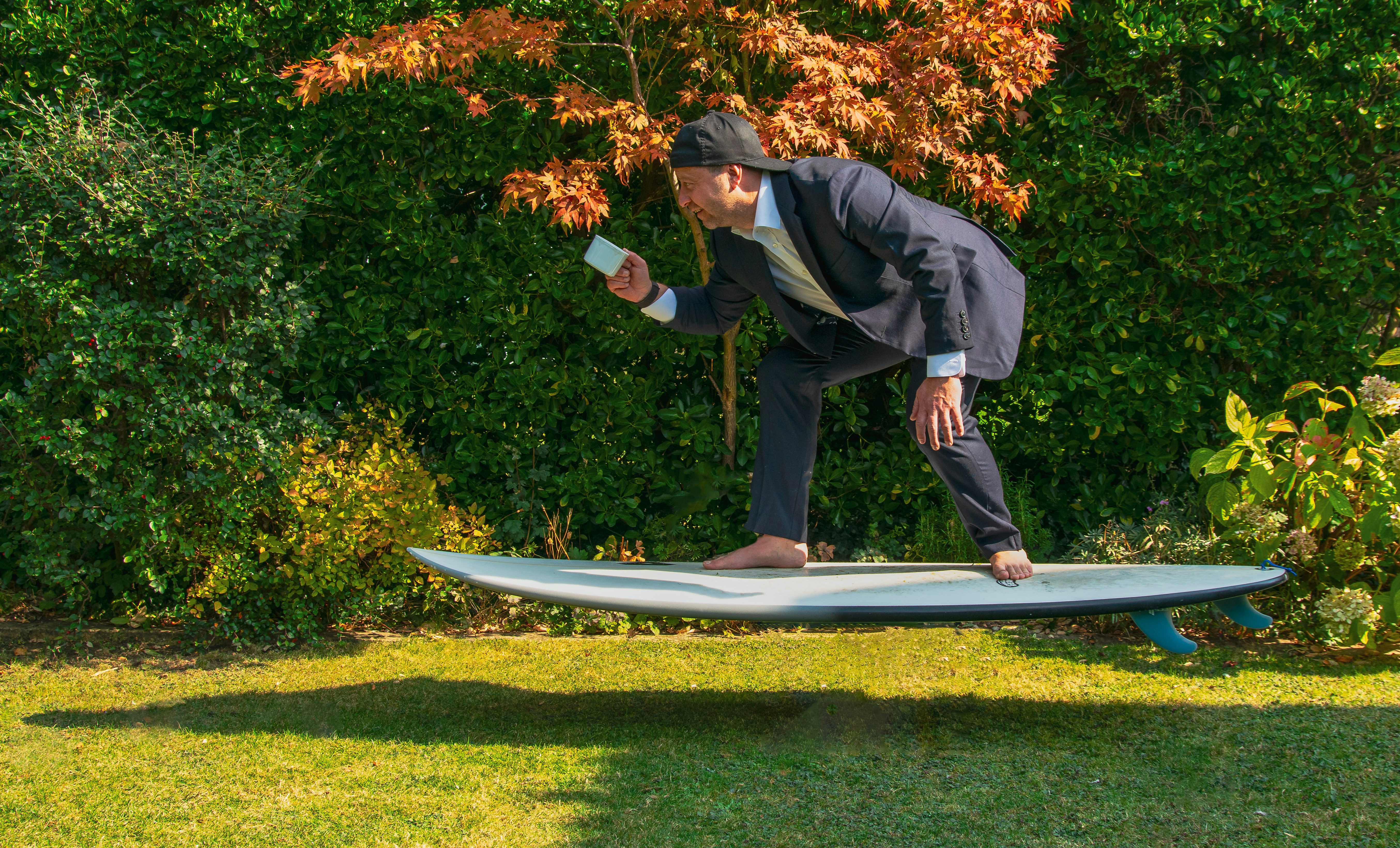 A man in a suit is balancing on a surfboard