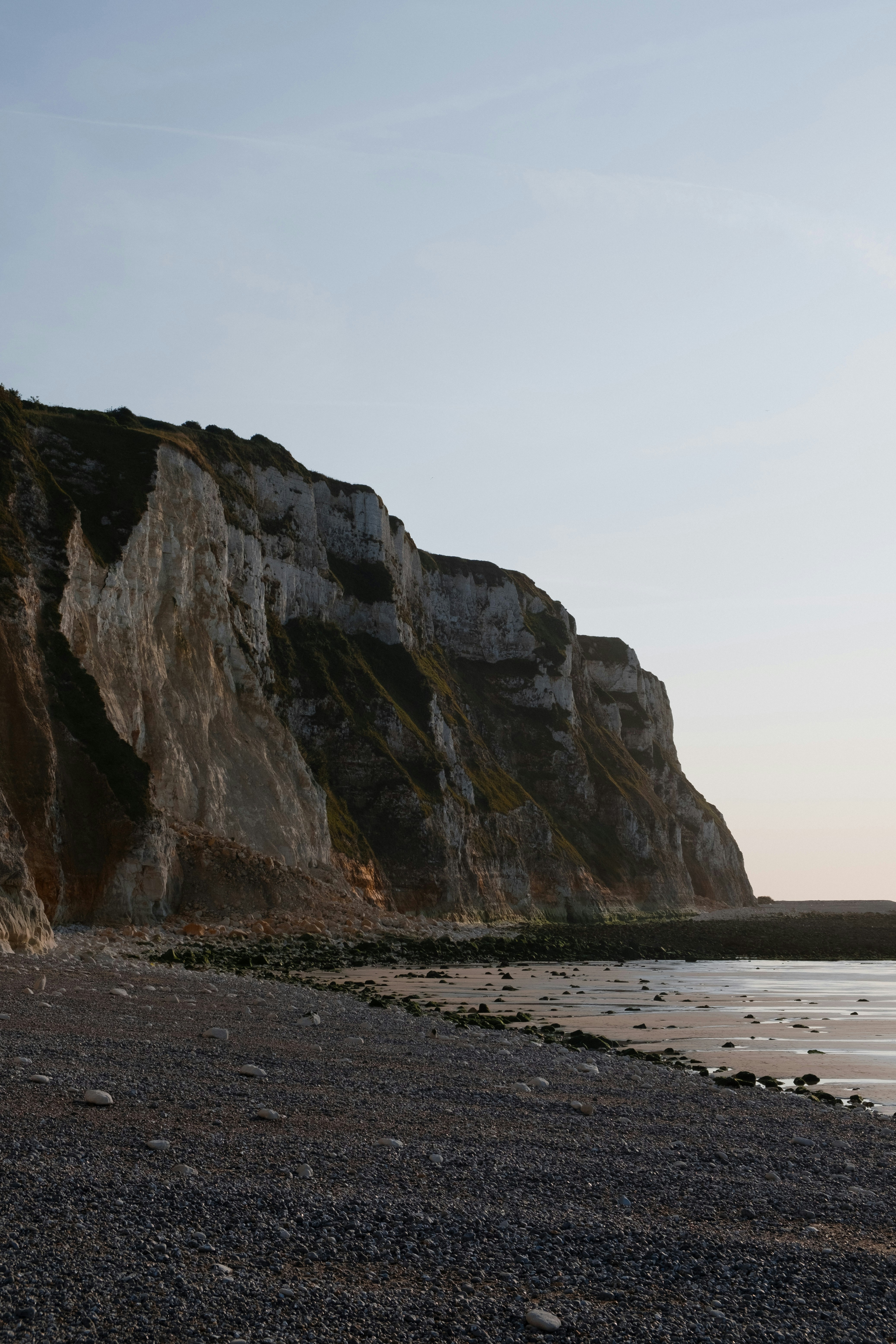 A person standing on a beach with a surfboard