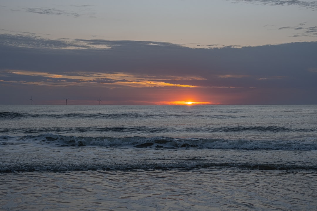 The sun is setting over the ocean on a cloudy day,
