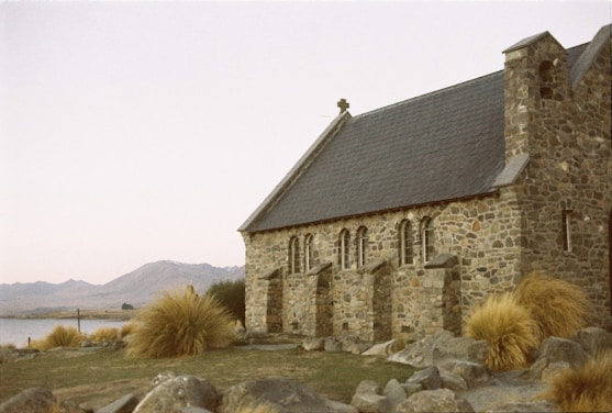 An old stone church with a lake in the background