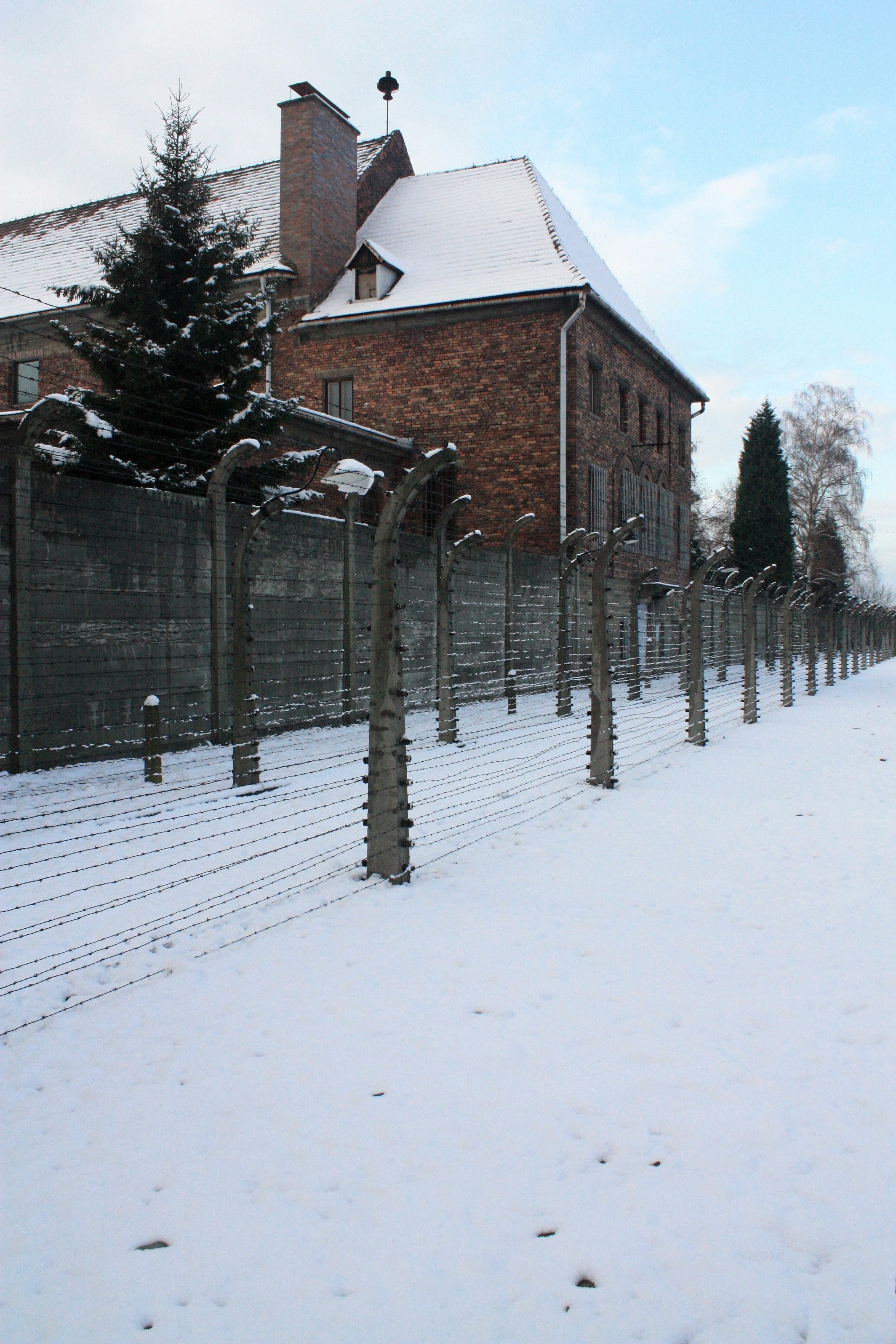 A fence that is next to a building in the snow