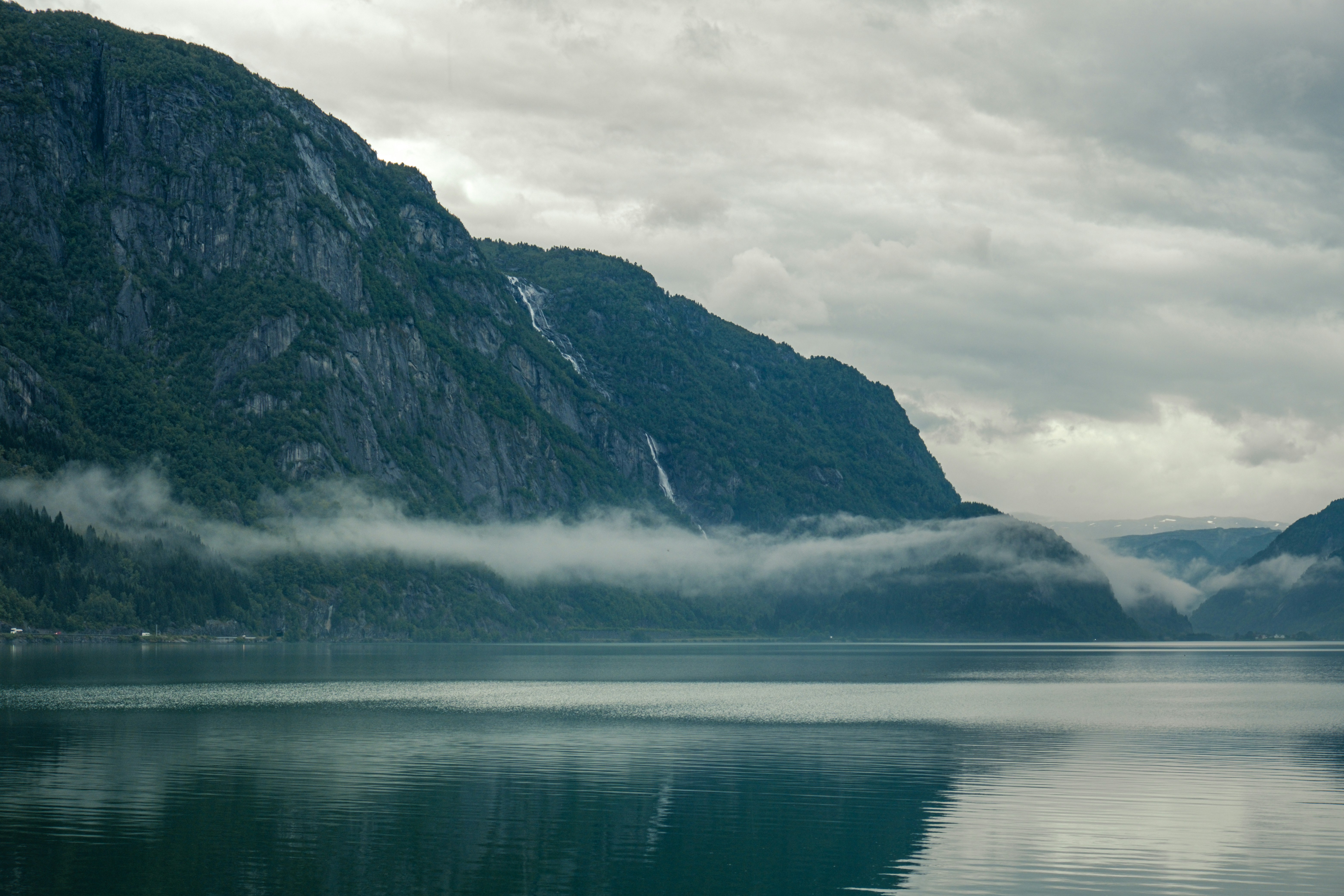 A body of water surrounded by mountains under a cloudy sky