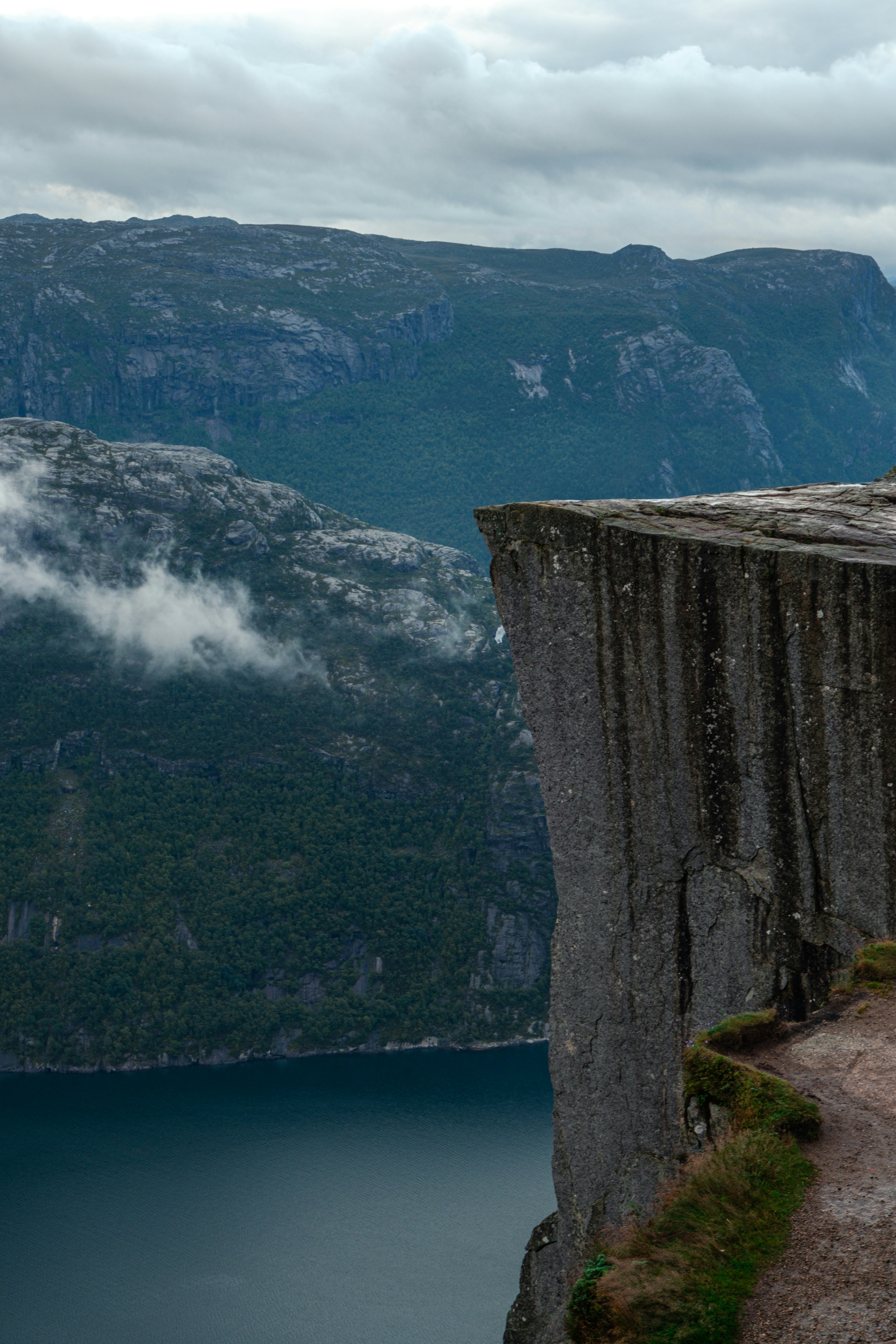 A man standing on top of a cliff next to a body of water