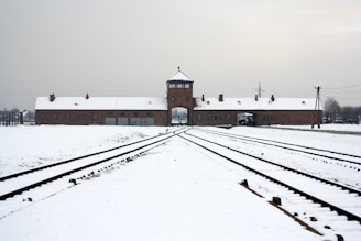 A train track in front of a building covered in snow