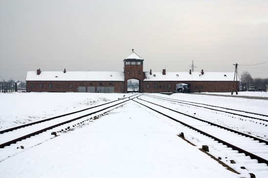 A train track in front of a building covered in snow