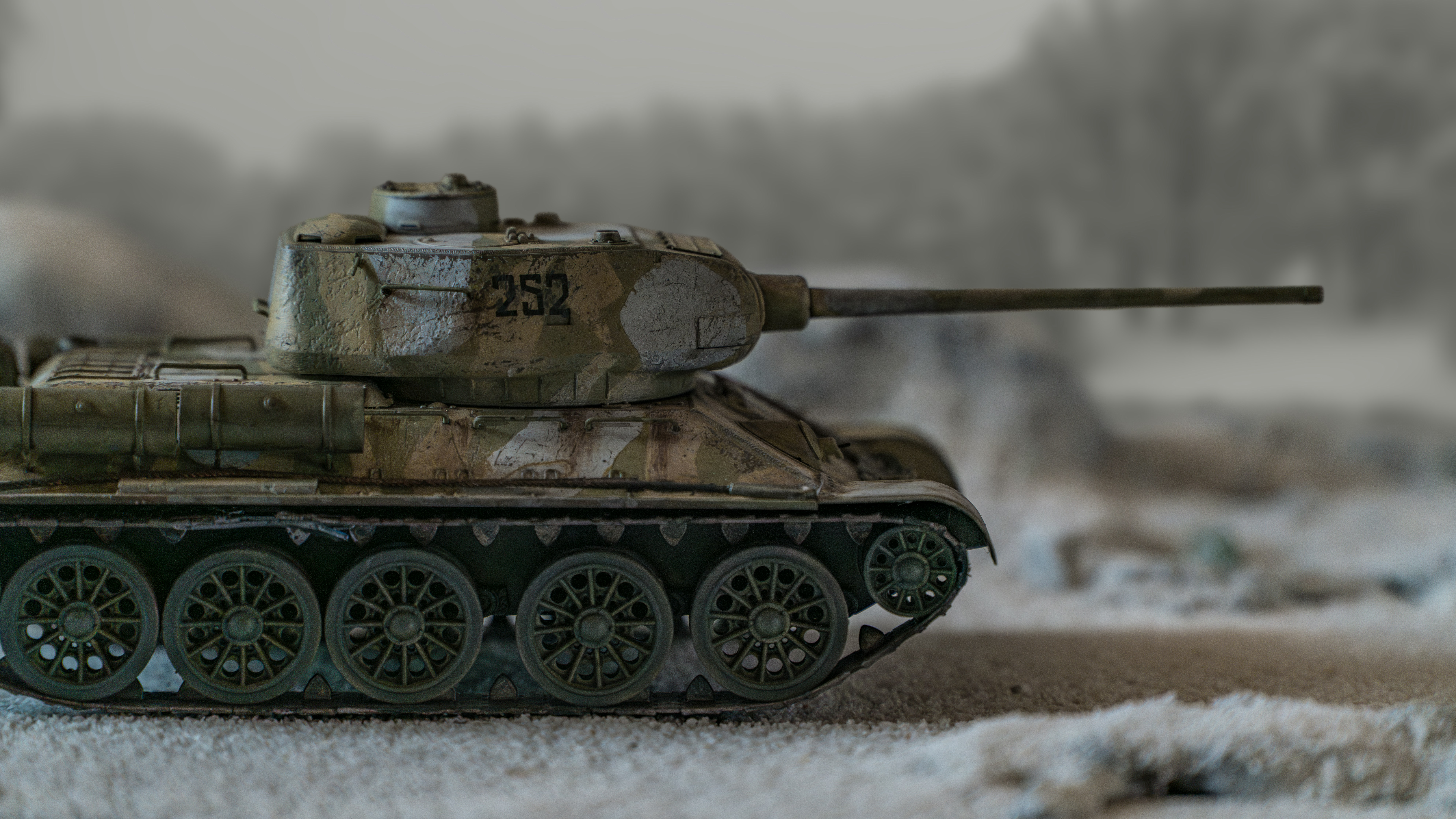 A toy tank sitting on top of a snow covered ground