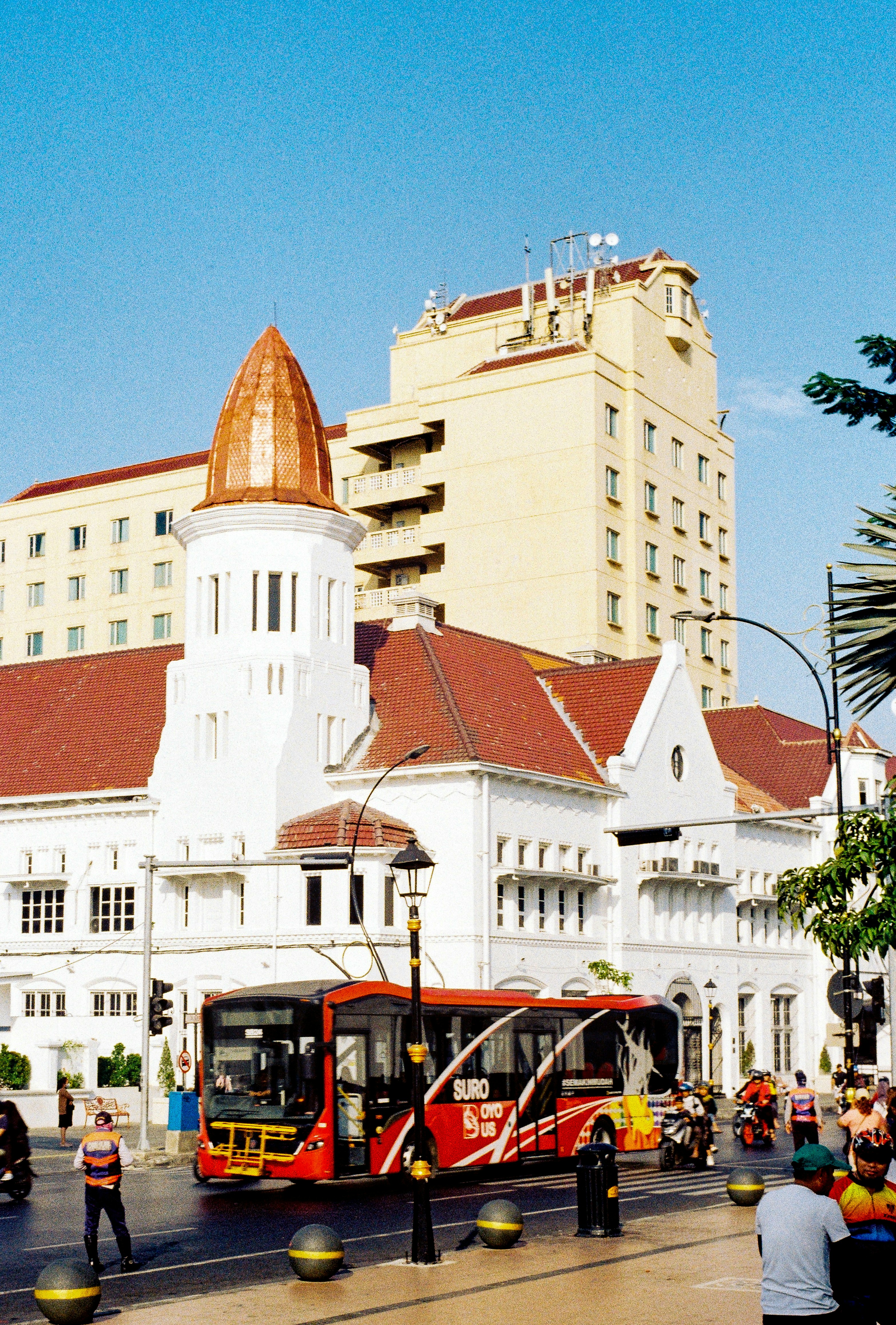 A red bus driving down a street next to tall buildings