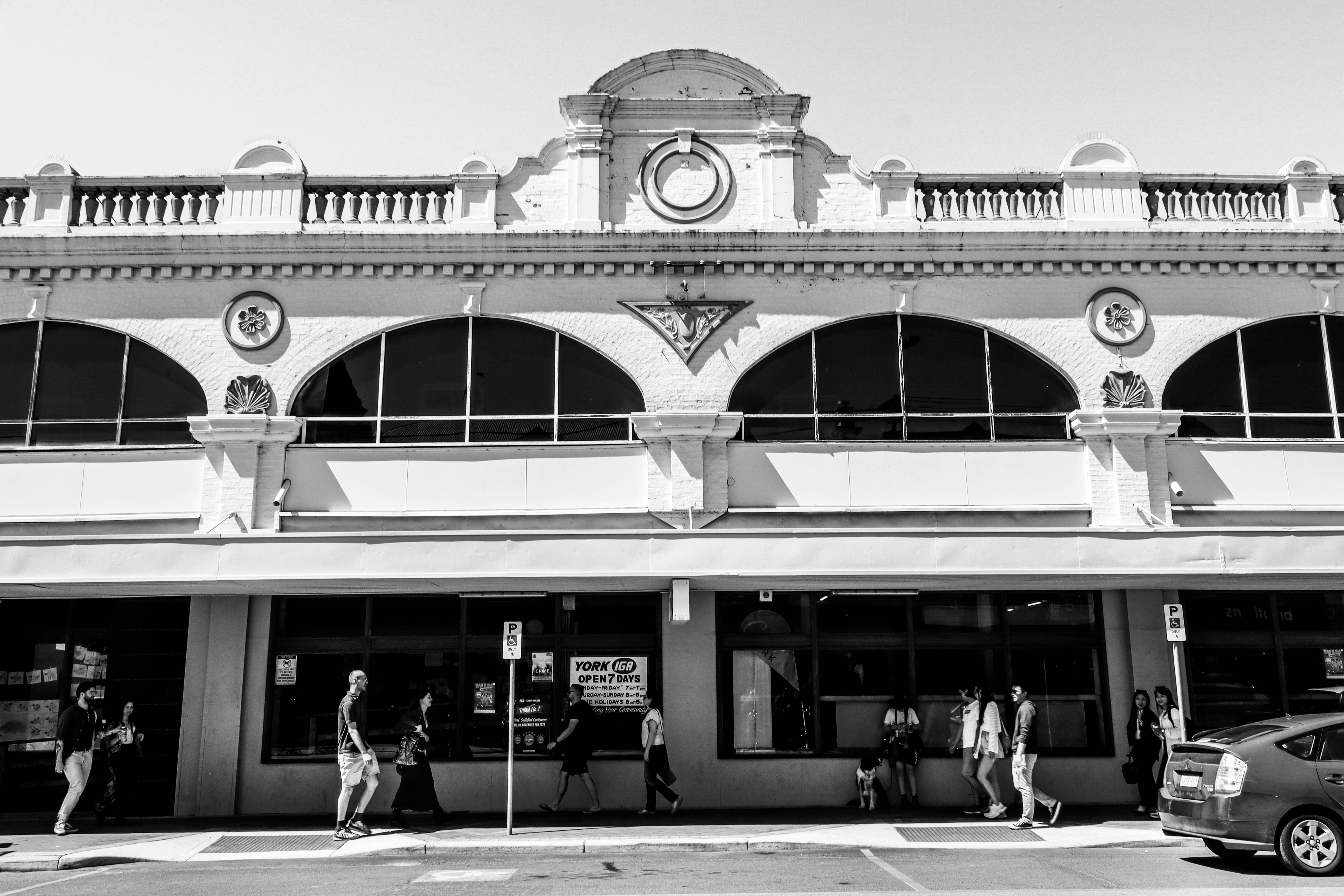 A black and white photo of people walking in front of a building