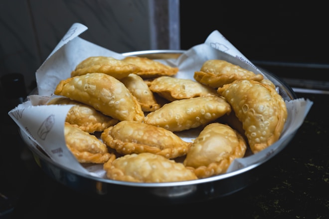 A metal bowl filled with fried food on top of a stove
