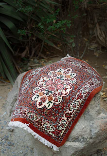 A red and white oriental rug sitting on top of a rock