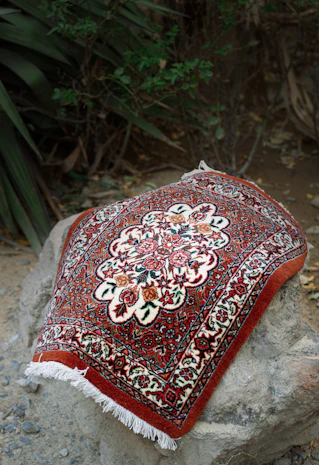 A red and white oriental rug sitting on top of a rock
