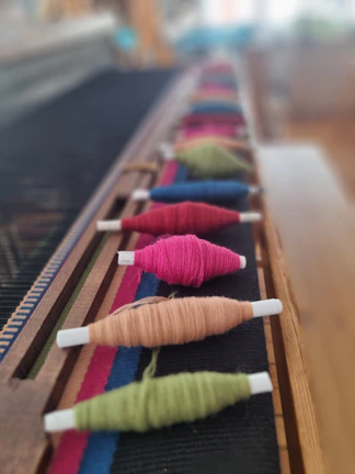 A row of different colored thread spools on a table