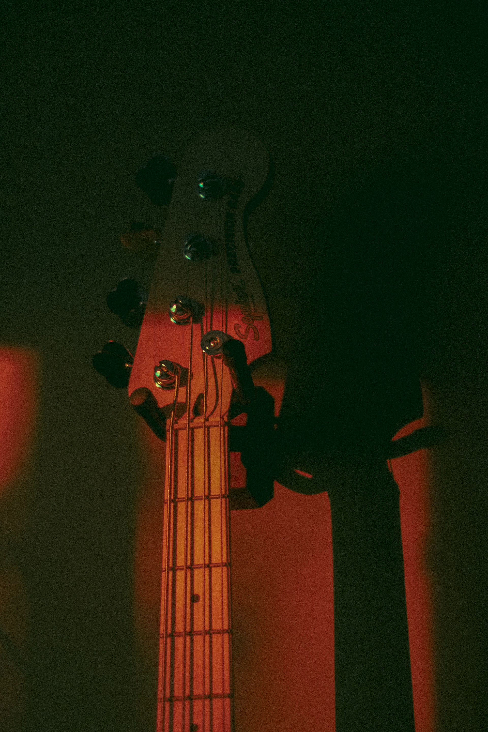 A close up of a bass guitar in a dark room