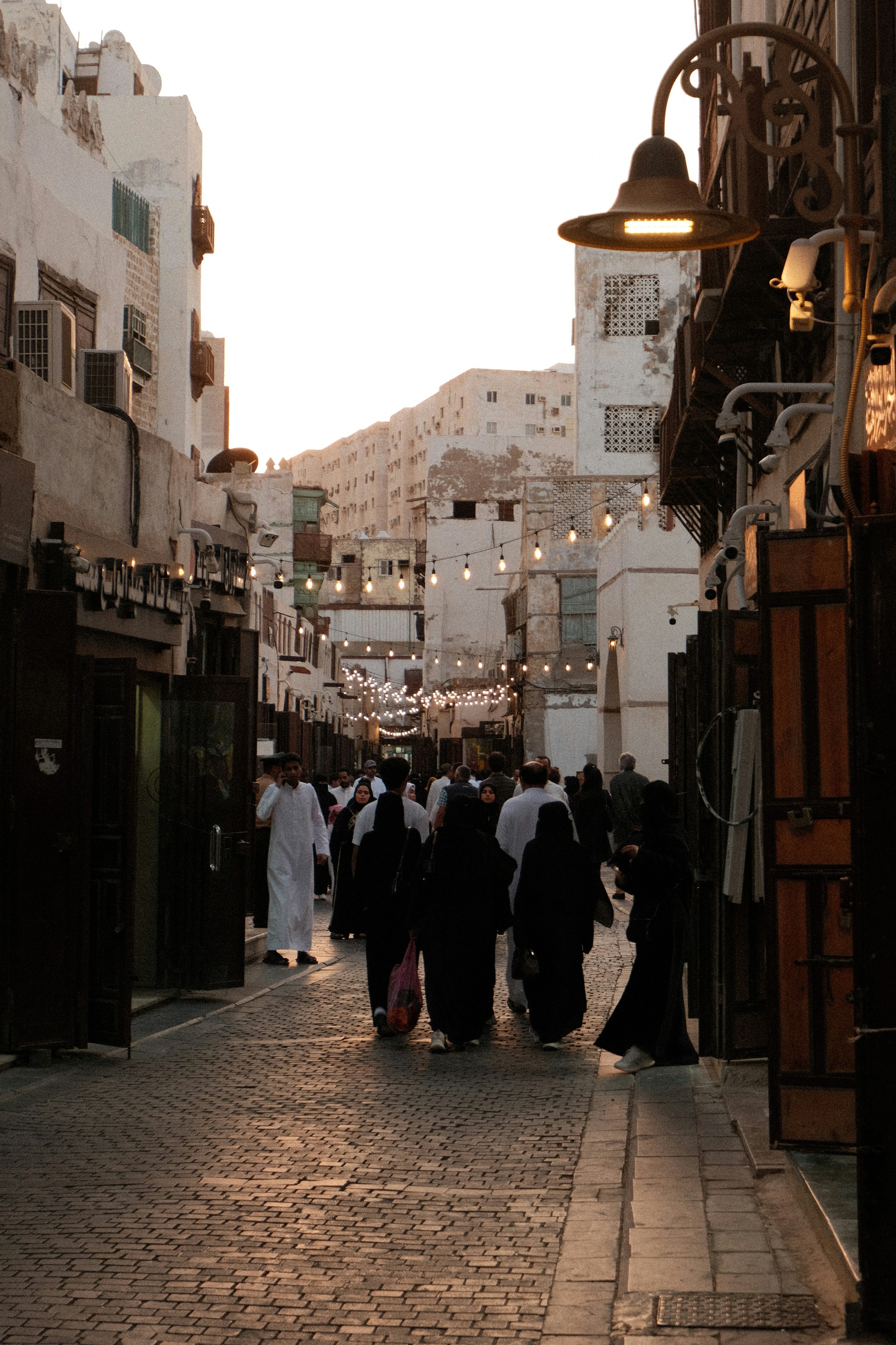A group of people walking down a street next to tall buildings