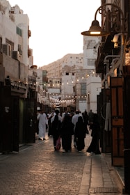 A group of people walking down a street next to tall buildings