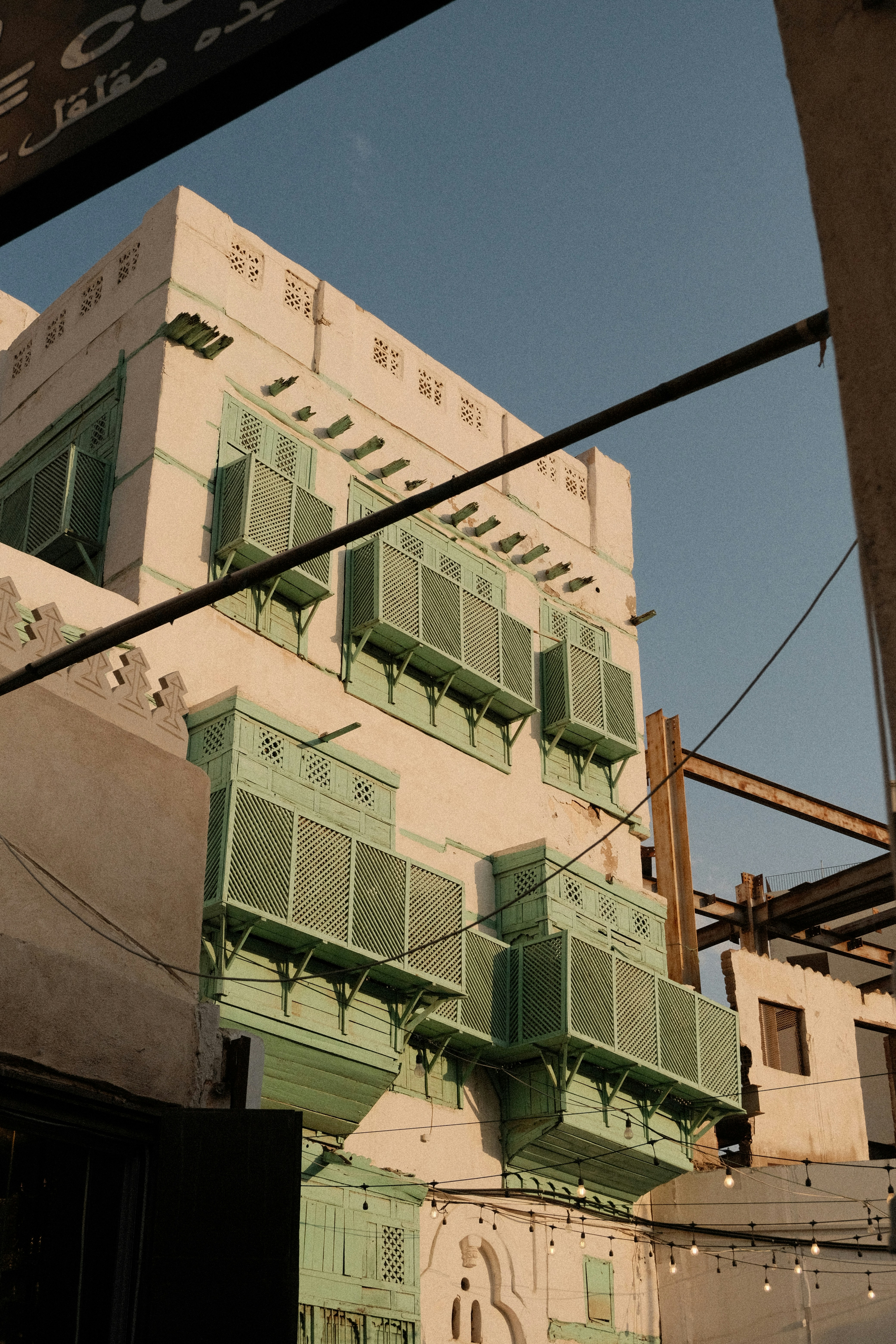 A tall building with green shutters next to a traffic light