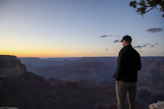 A man standing at the edge of a cliff at sunset