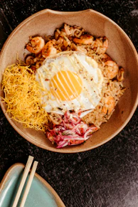 A bowl of food on a table with chopsticks
