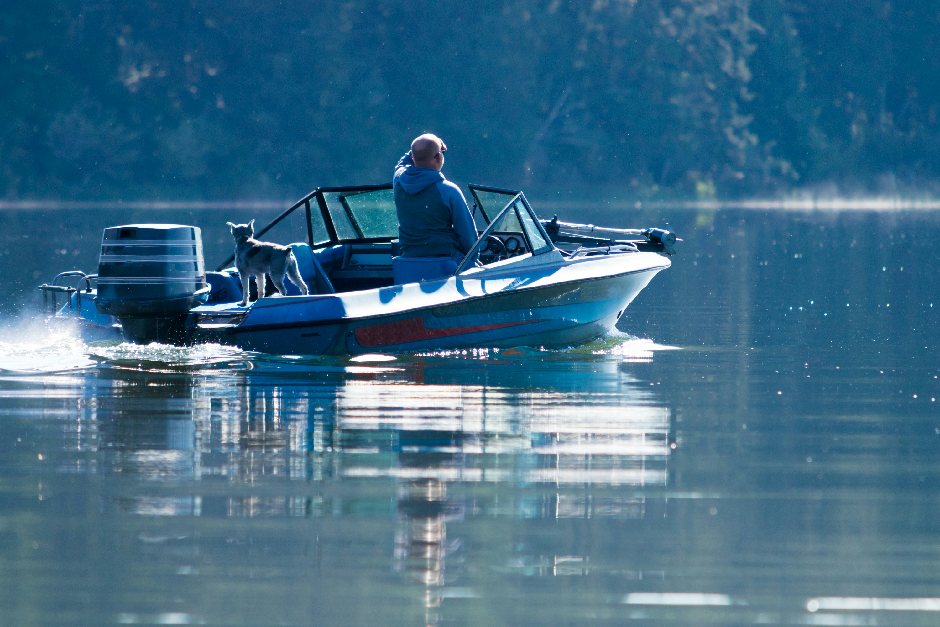 A man riding on the back of a blue boat