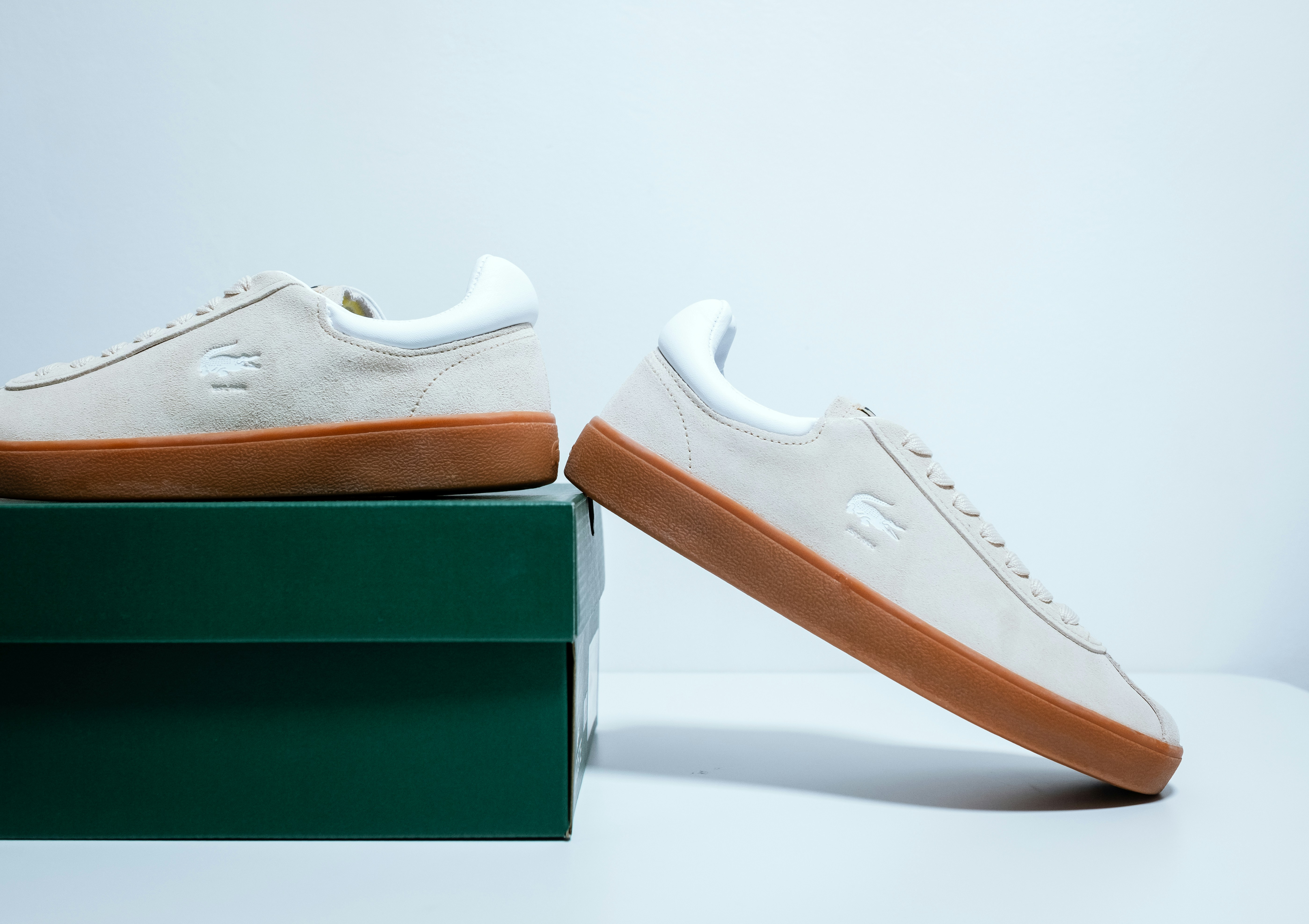 A pair of white sneakers sitting on top of a green box