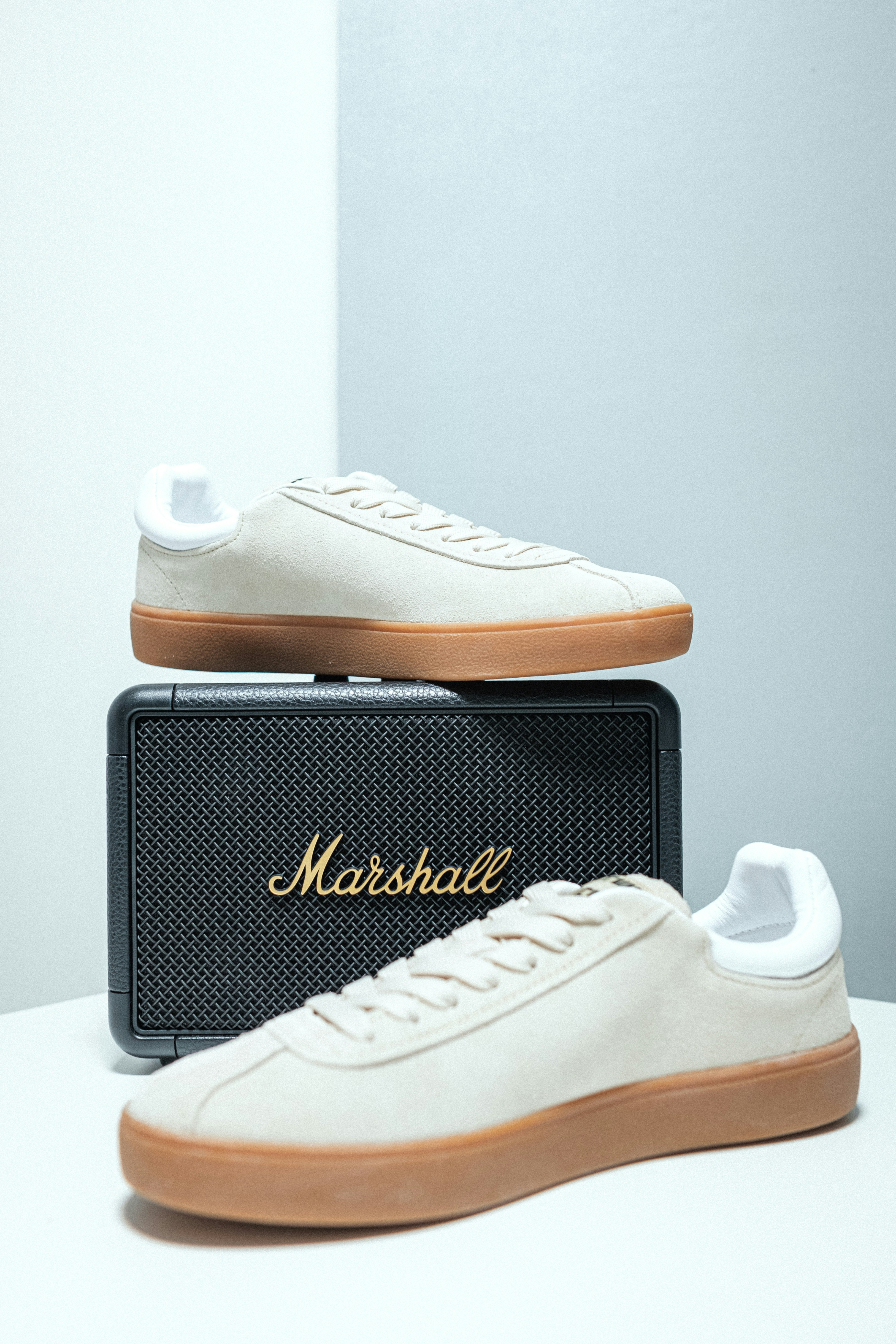 A pair of white sneakers sitting on top of a speaker