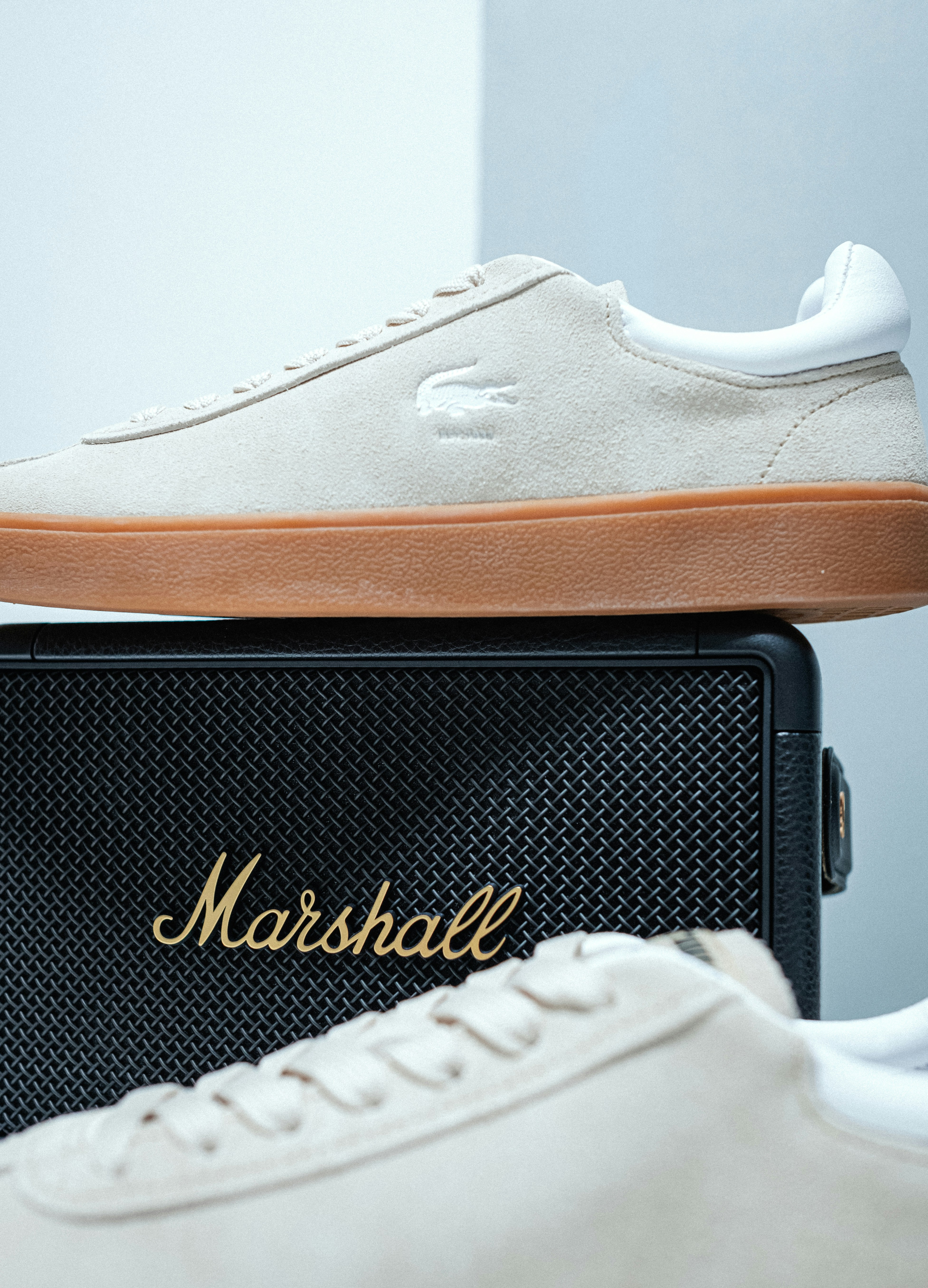 A pair of white tennis shoes sitting on top of a speaker