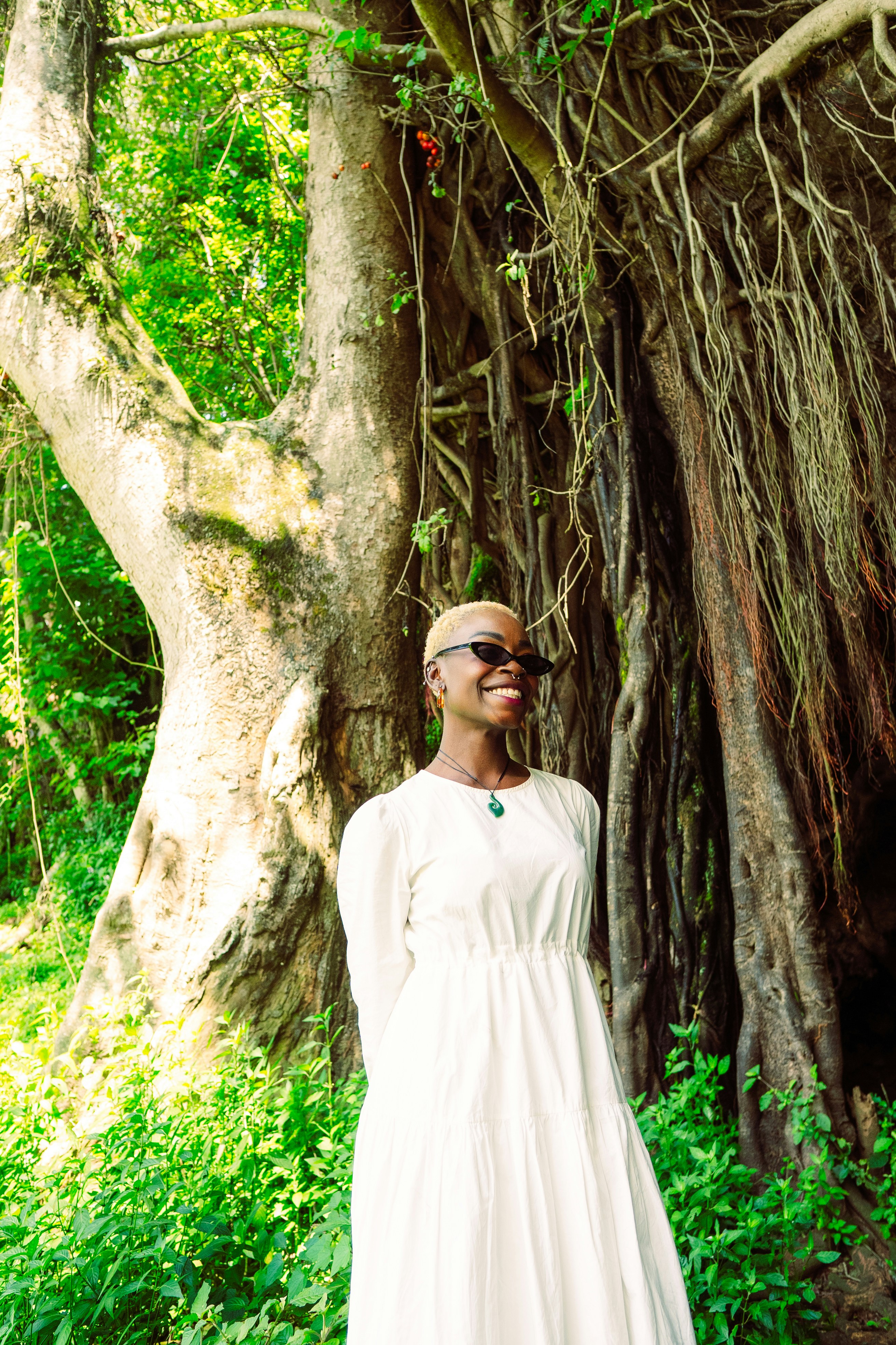 Uma mulher em um vestido branco em pé na frente de uma árvore