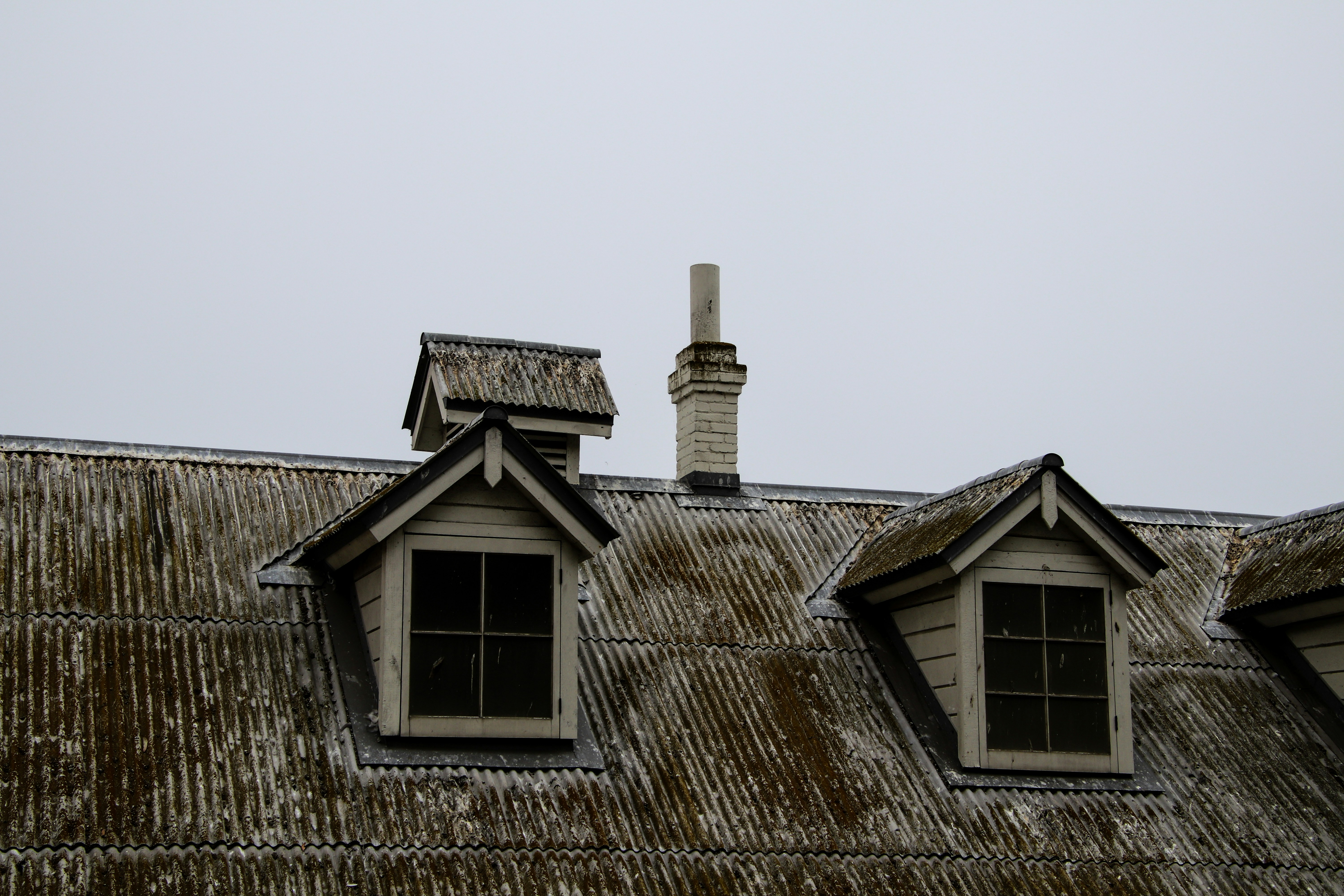 An airplane flying over a roof with two windows