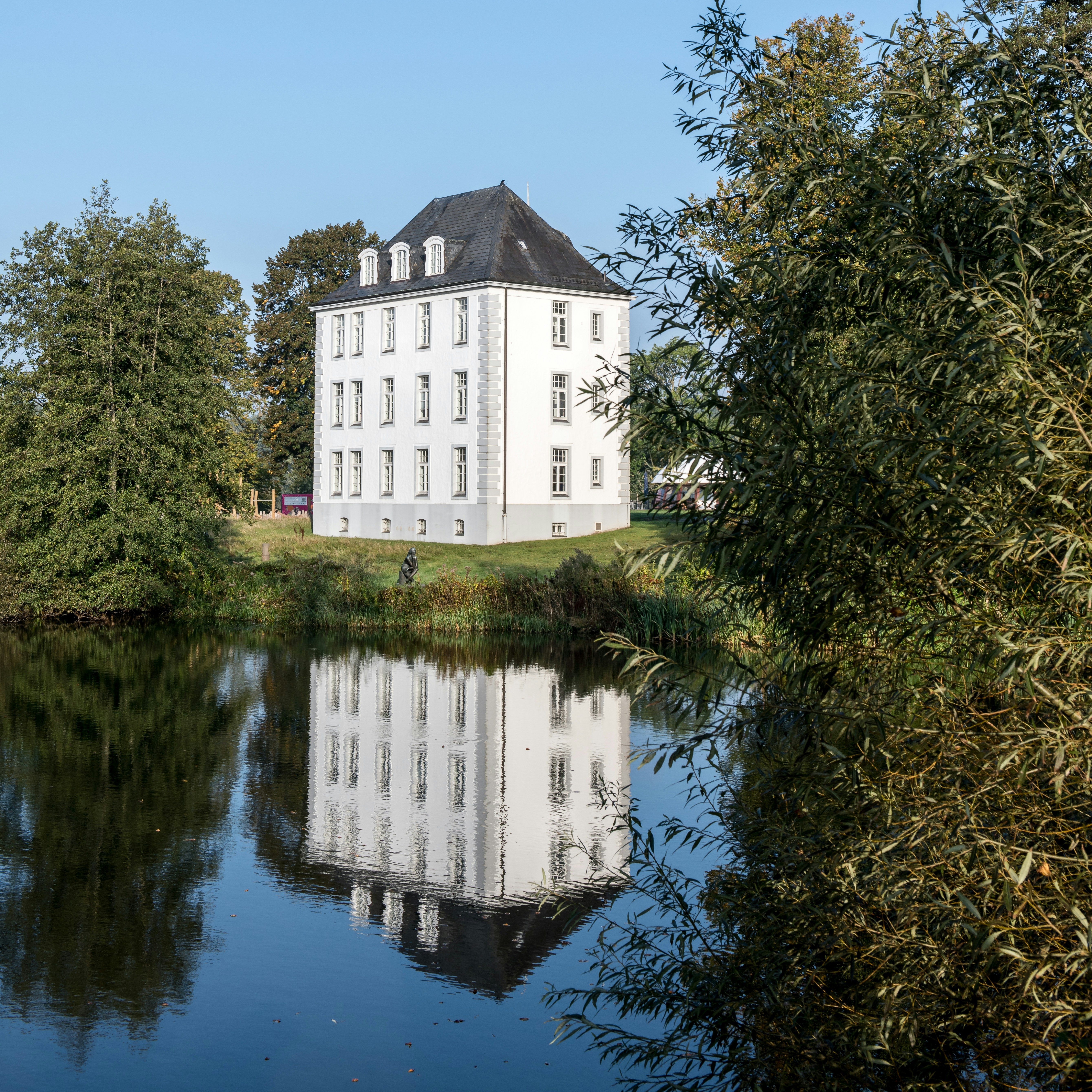 A large white building sitting on top of a lush green field